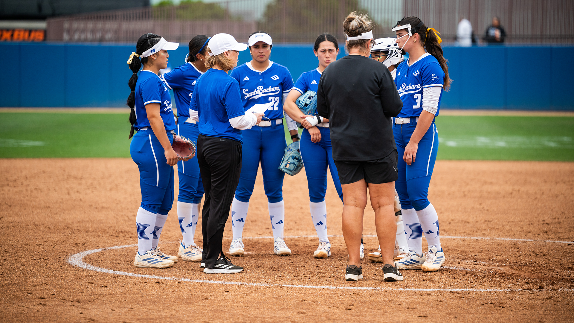 Softball team huddle at the pitchers circle. 