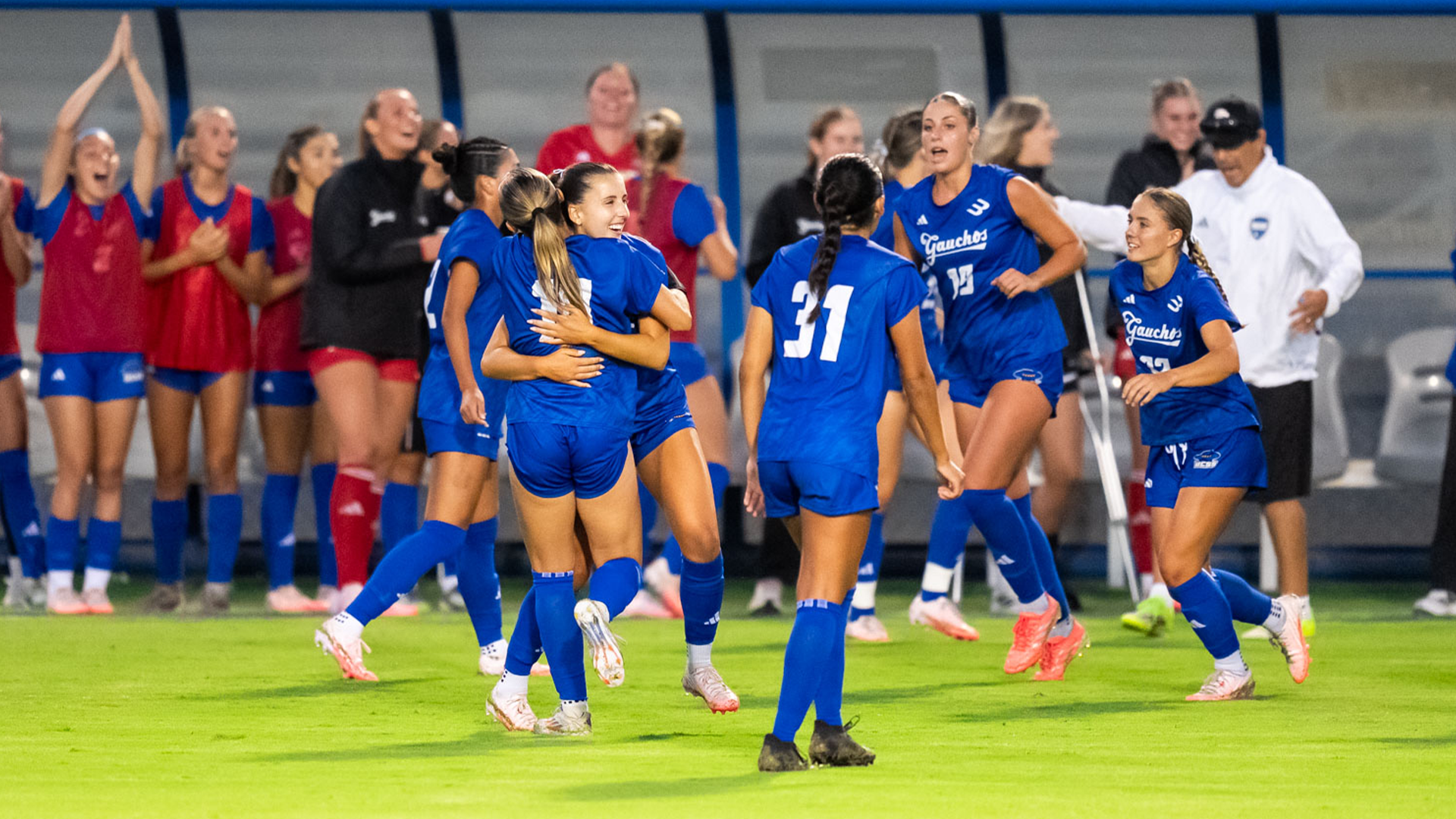 Women's Soccer celebrates after a no-goal call was overturned to a goal. The girls are hugging each other in celebration. 