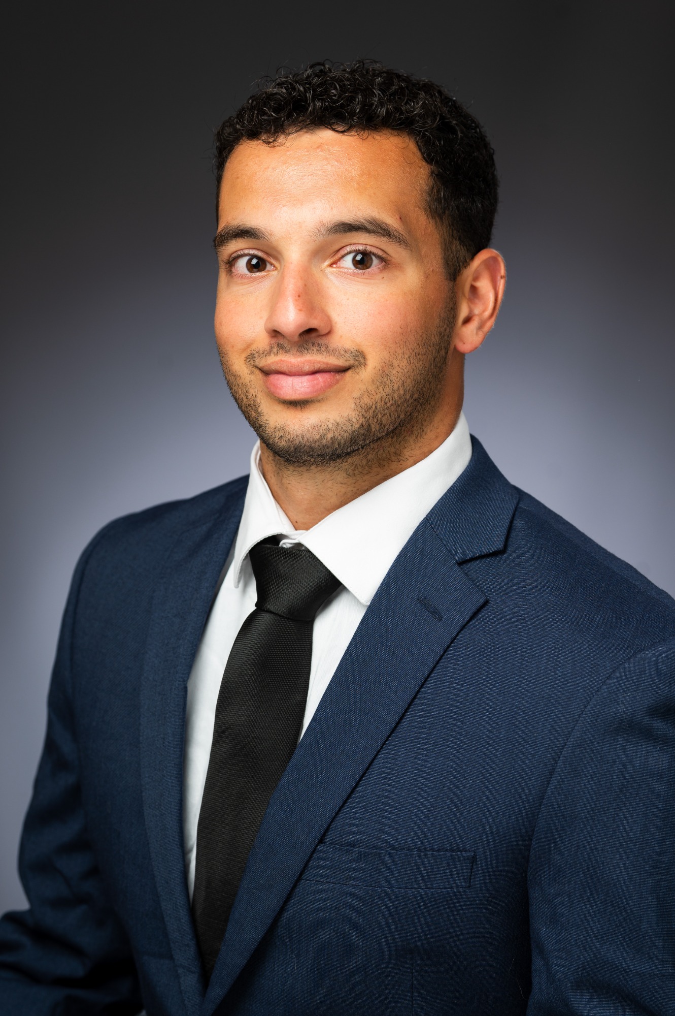 A portrait of Ashwin Morales in a suit.