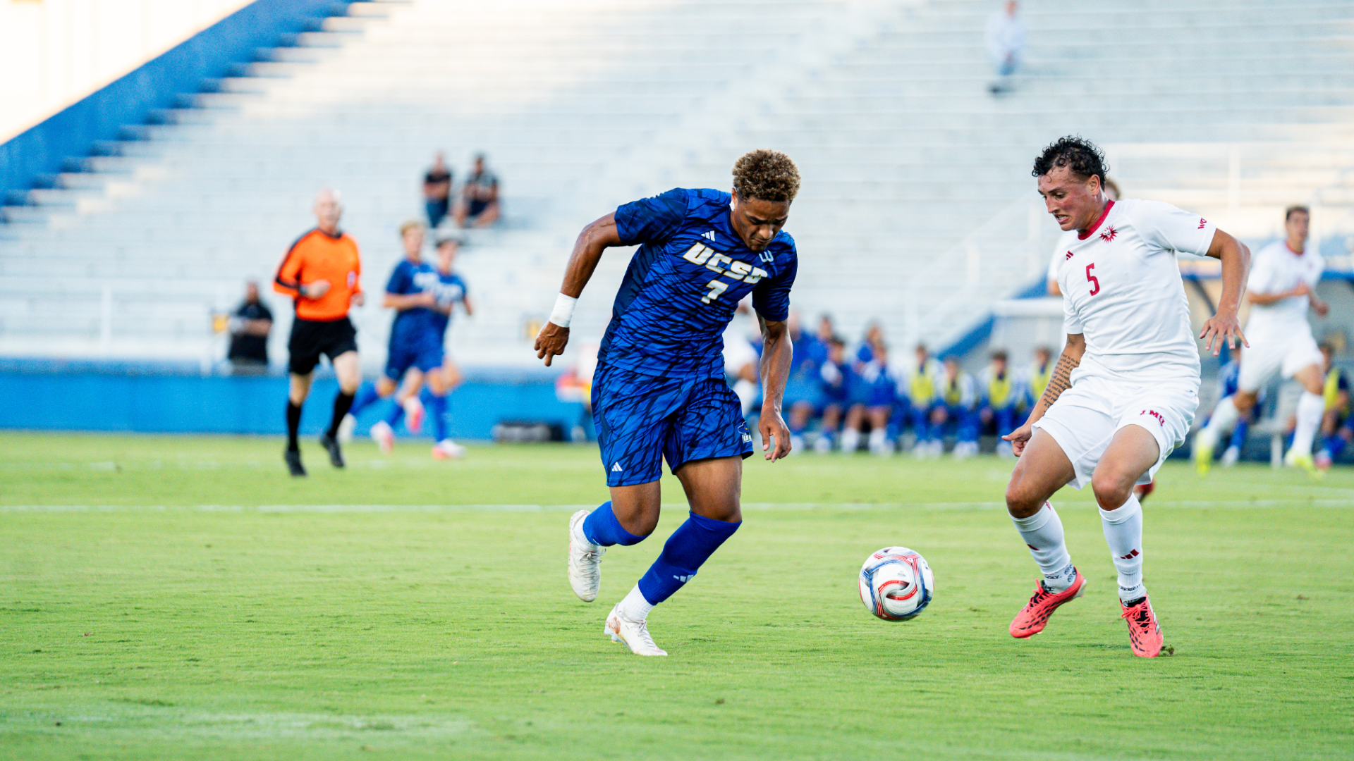 #7 Donovan Sessoms puts his head down and dribbles past an LMU defender
