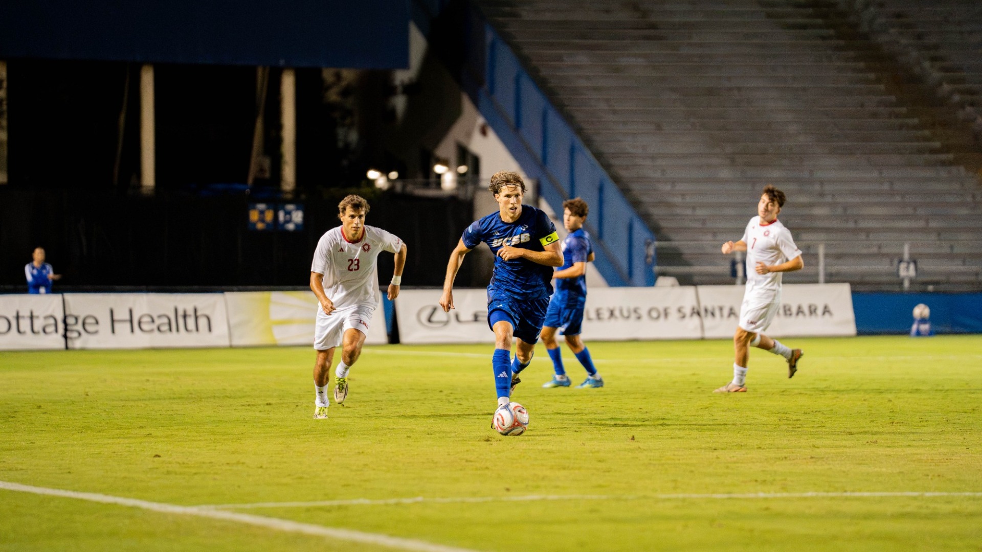 #4 Calle Mollerberg dribbles the ball up the field, leaving a pair of LMU defenders behind him, both craning their necks as he runs away