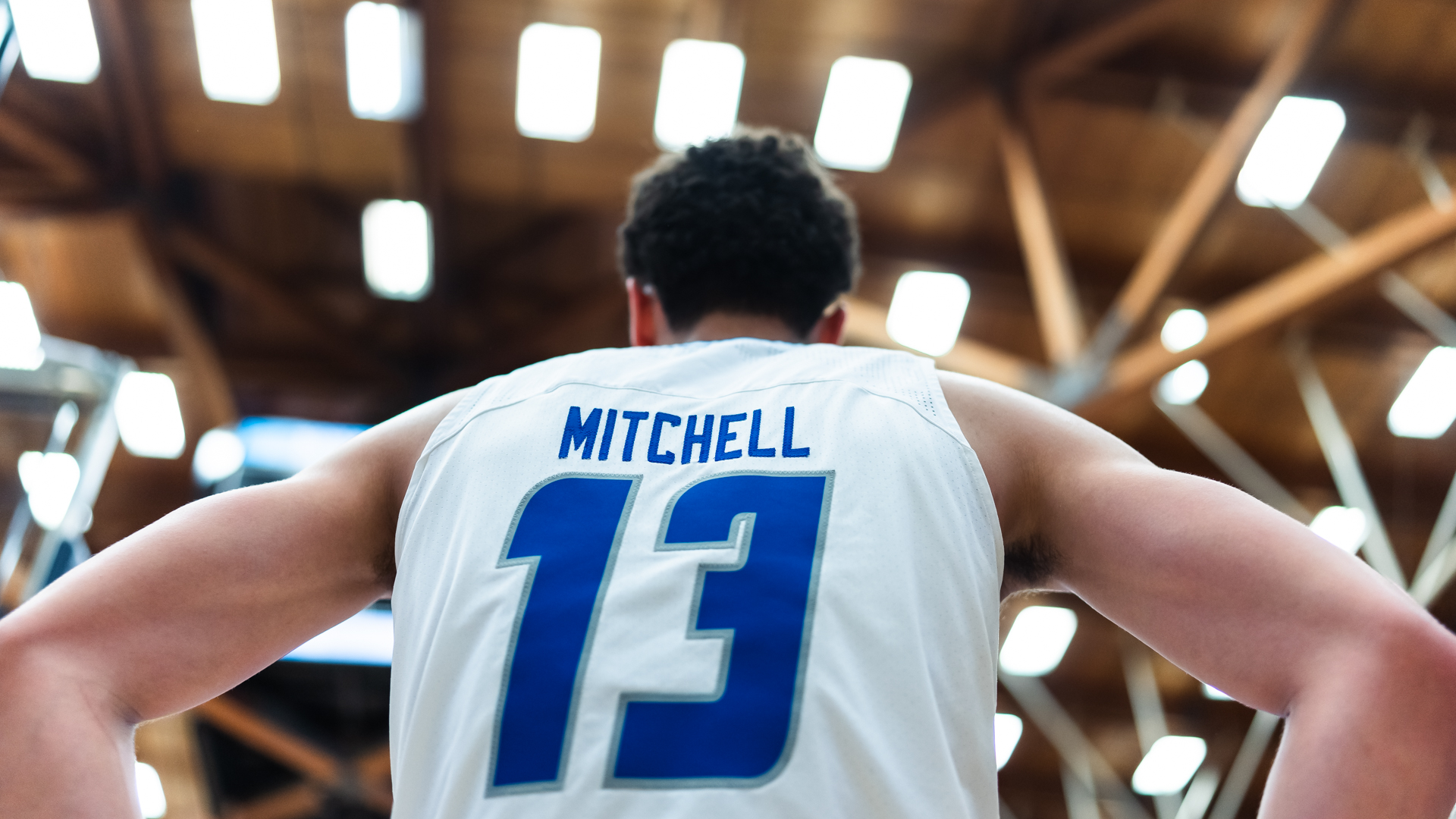 Ajay Mitchell standing with his back to the camera in his white UCSB jersey.