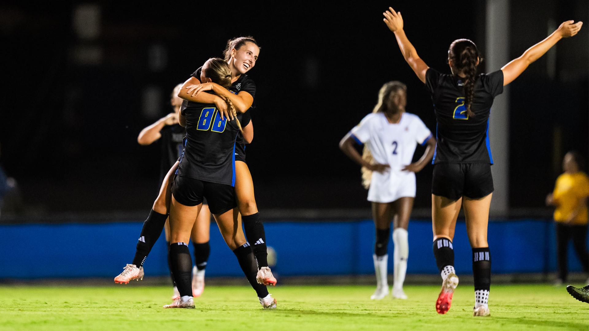 Caitlyn Simons (#13) celebrates with Hayden Halscheid (#88) after Halscheid scores a goal against San Jose State. Alondra Talamantes (#2) is in the foreground with her arms out celebrating as well. 