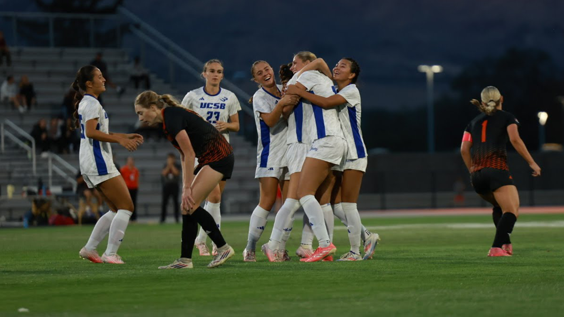 UC Santa Barbara Women's Soccer student-athletes celebrate after scoring a goal by hugging each other.