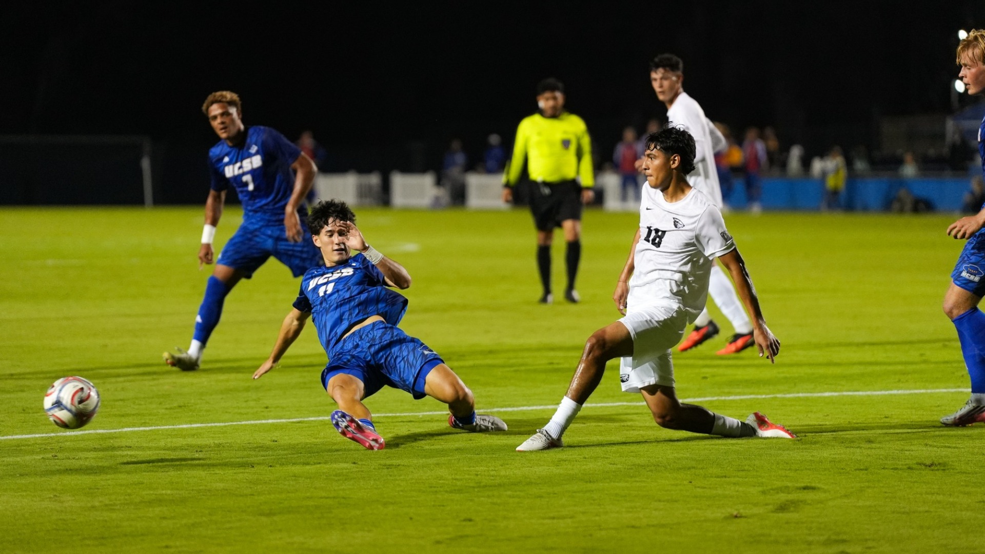 A Gaucho Men's Soccer player in the left side of the frame makes a sliding tackle to try and block from an Oregon State player, on the right side of the frame