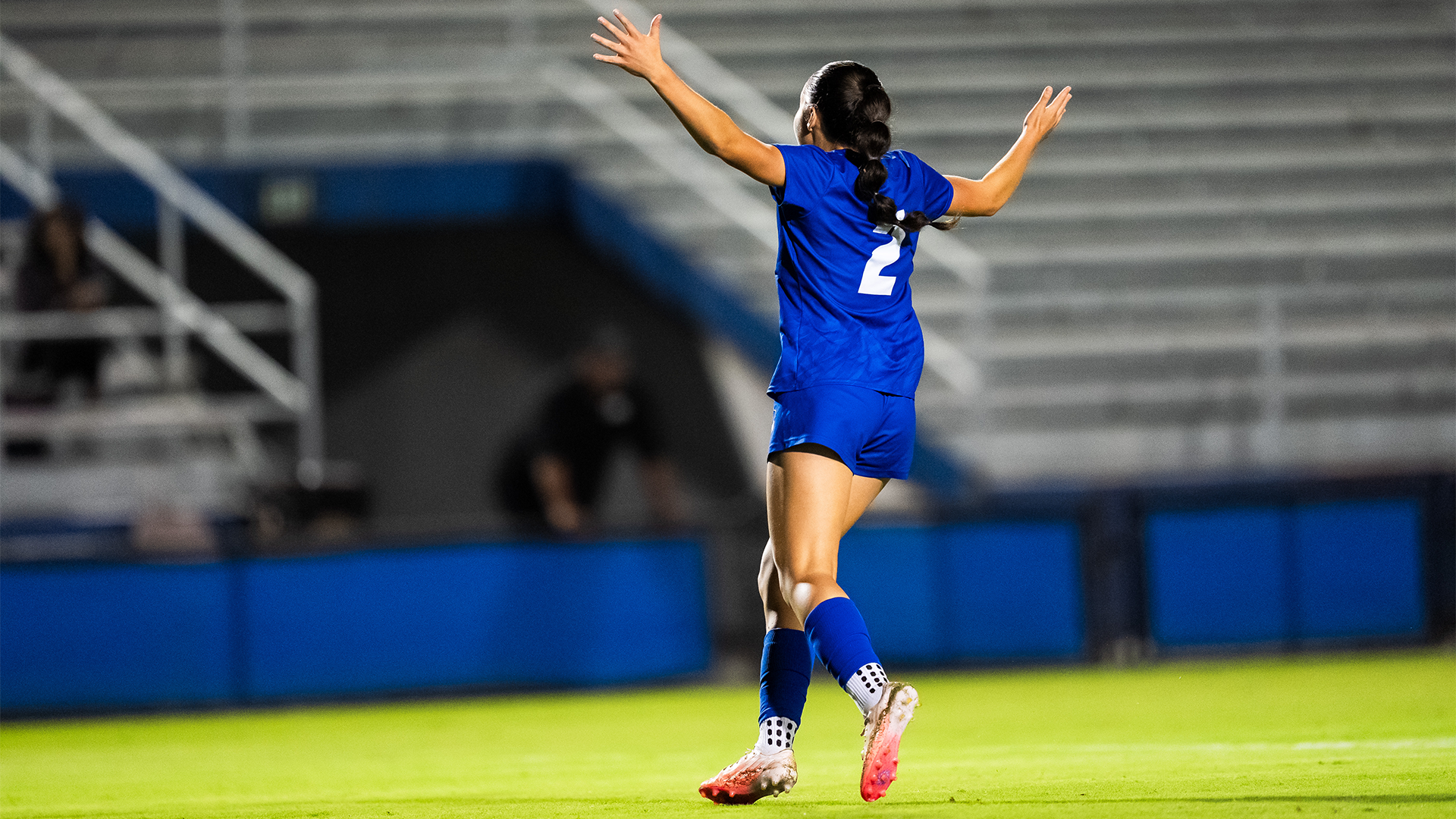 Alondra Talamantes (#2) celebrates her goal by raising her arms in the air.