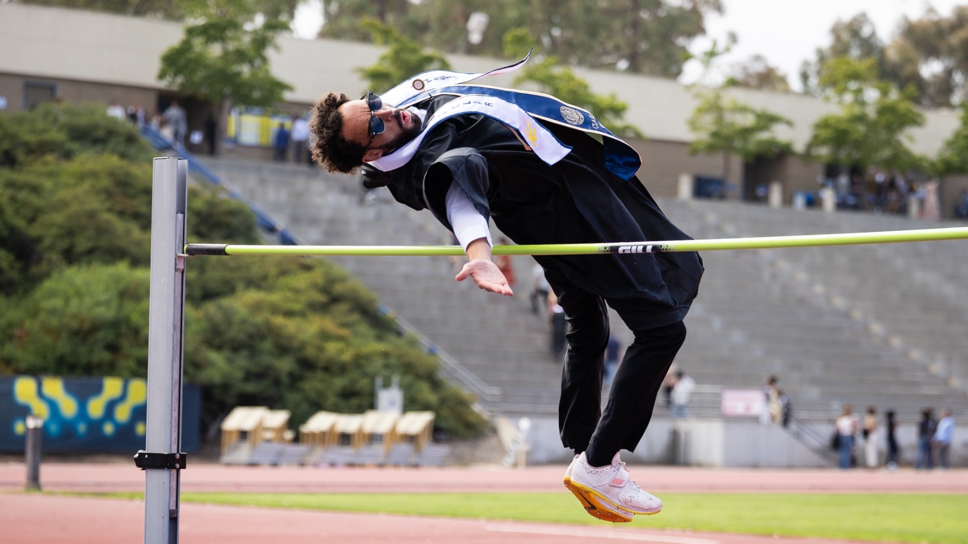 Miles Bennett does a high jump in his graduation regalia