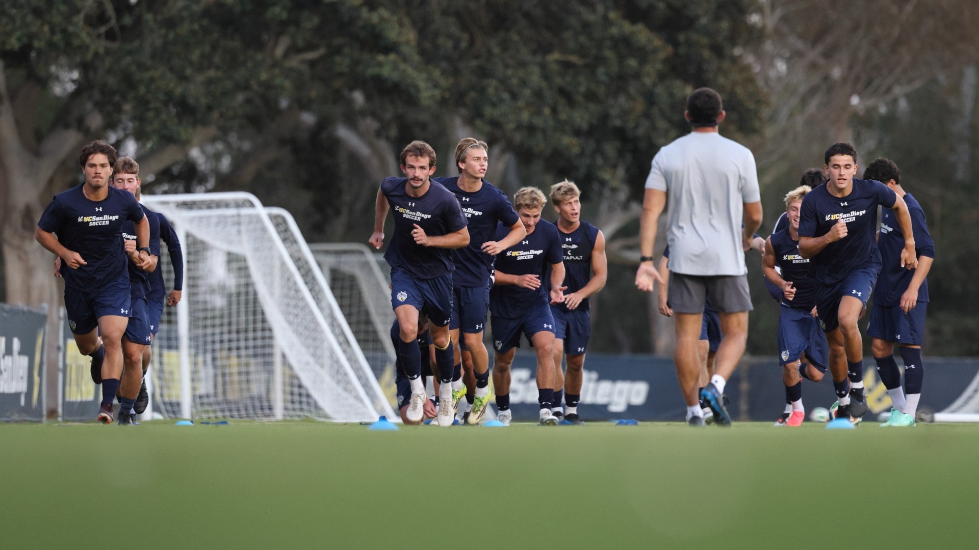 Men's Soccer players warming up by running sprints in a line