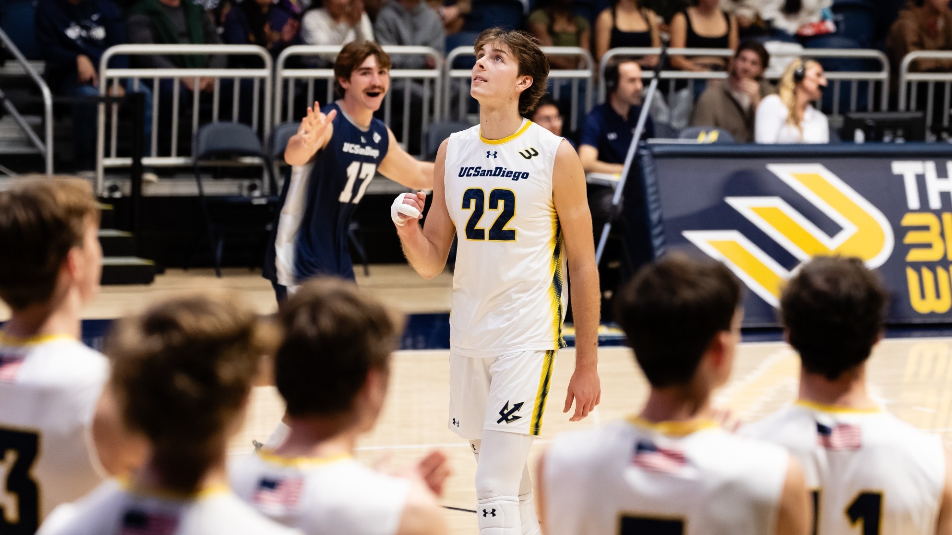Sebastiano Sani celebrates with a fist pump while looking up. His teammate smiles in the background.