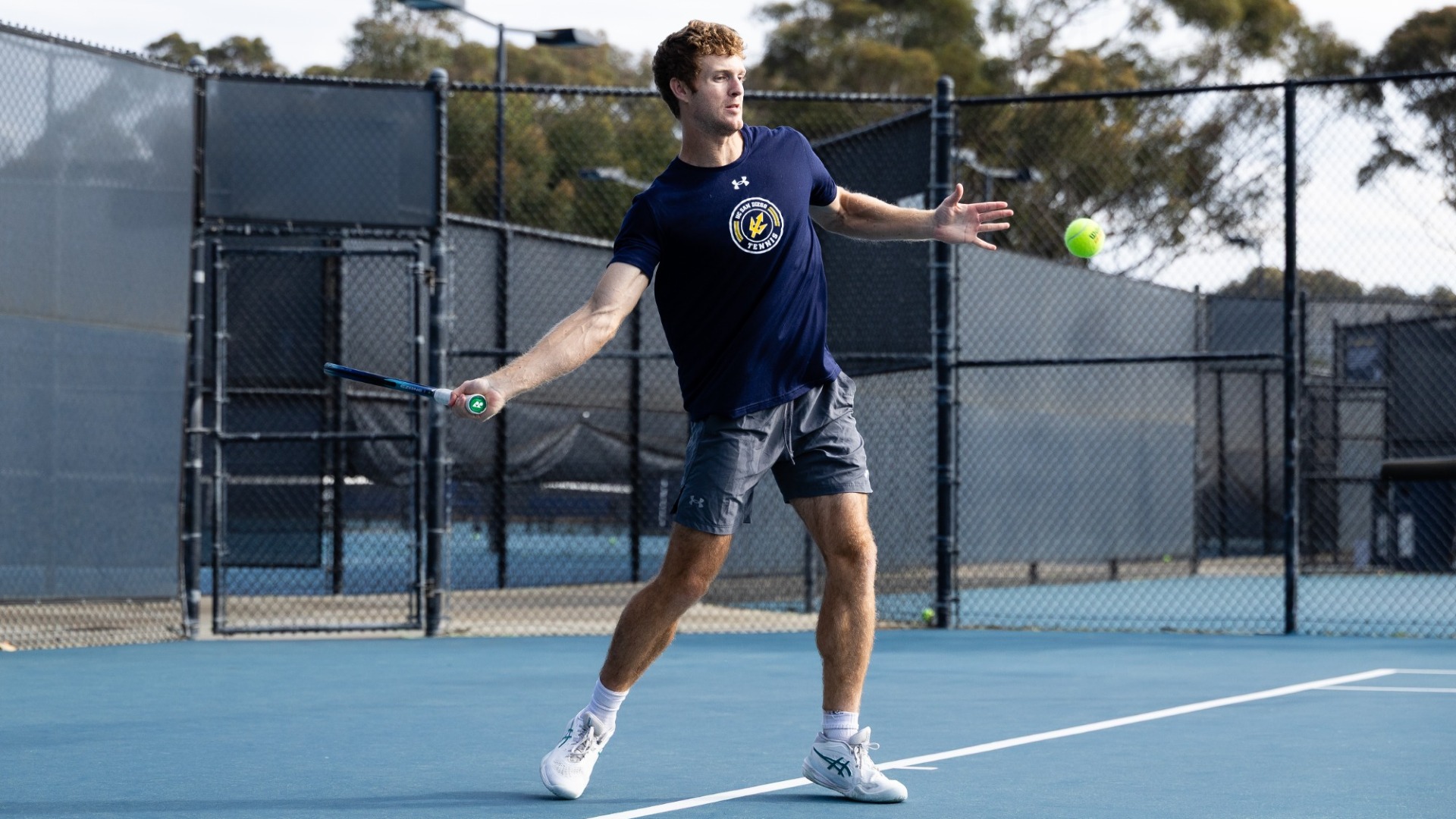 Oliver Worth prepares to hit a tennis ball with a frehand shot