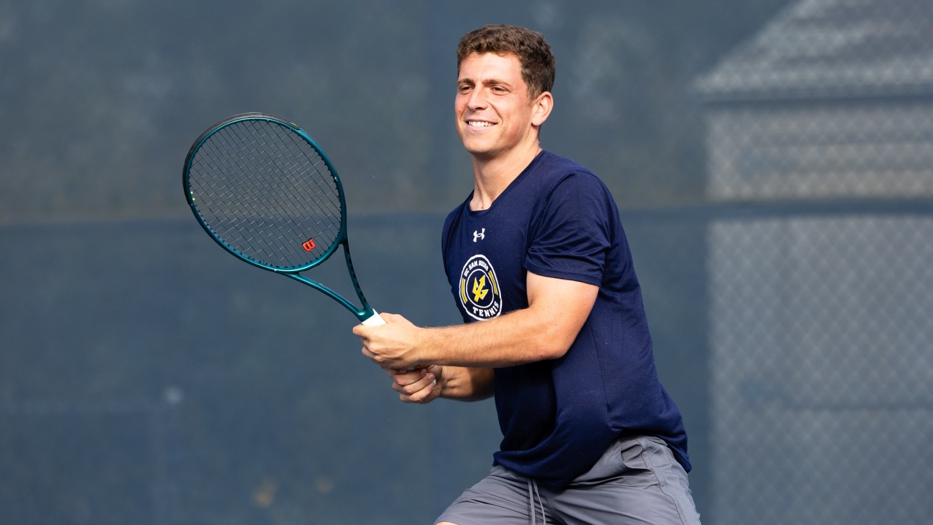 Yaron Guberman finishes return shot with racquet in hand and smile on face