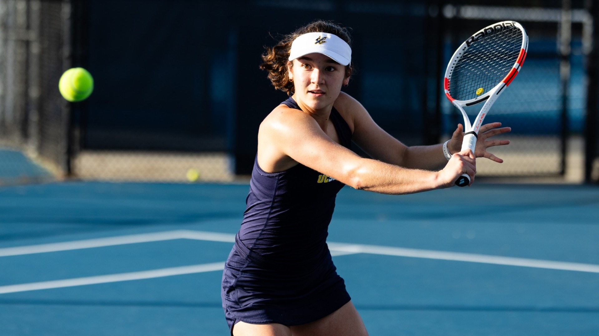 Olivia Allegre prepares to hit a forehand return shot with a tennis ball in frame