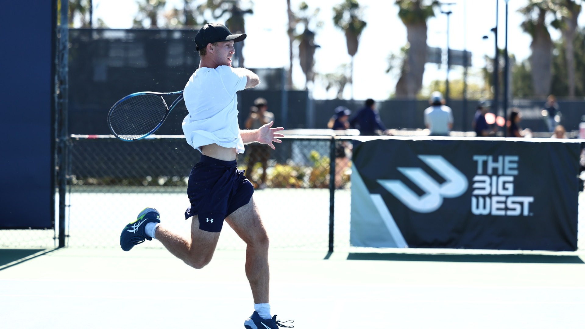 Oliver Worth hits a forehand return shot on a blue court