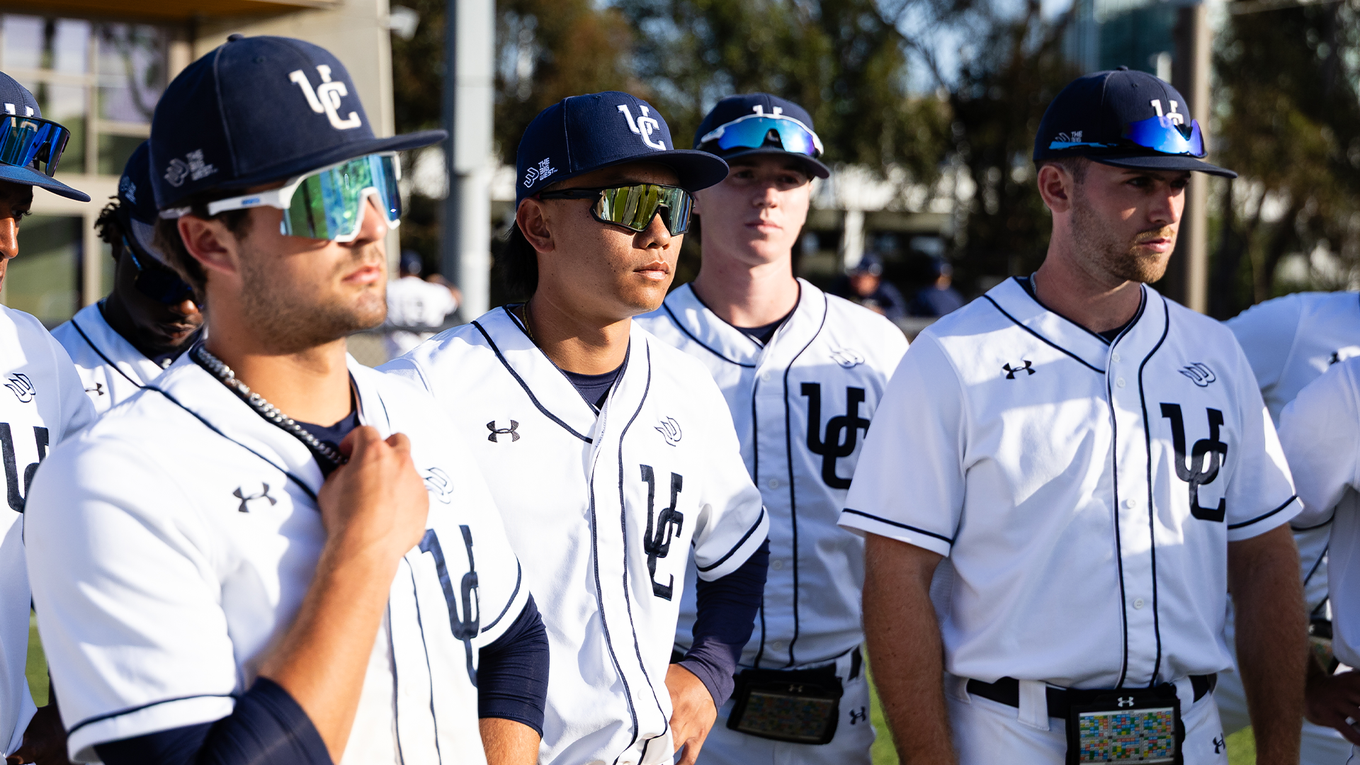 Baseball players in white uniforms gather in huddle