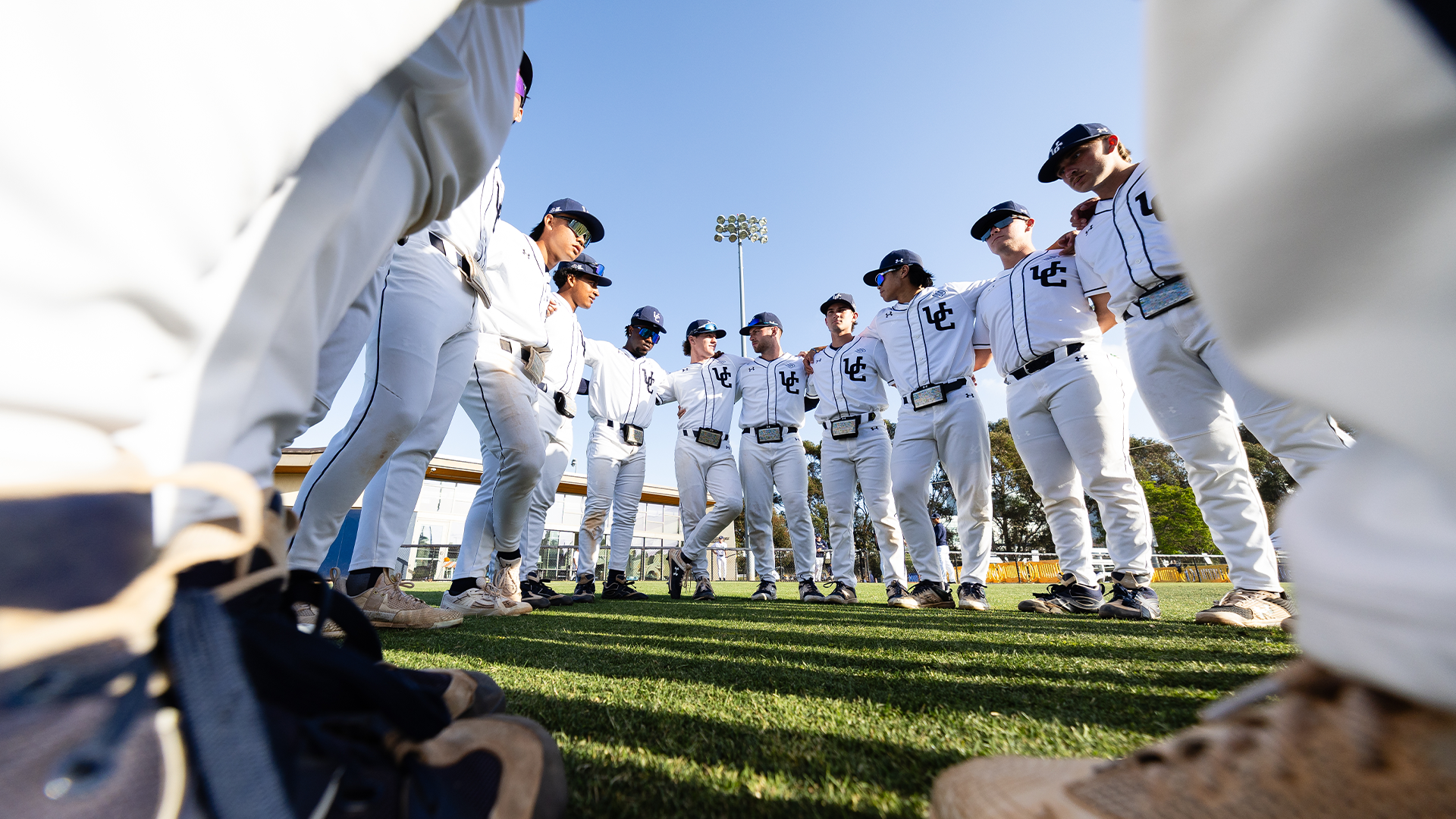 Baseball team huddles in white uniforms