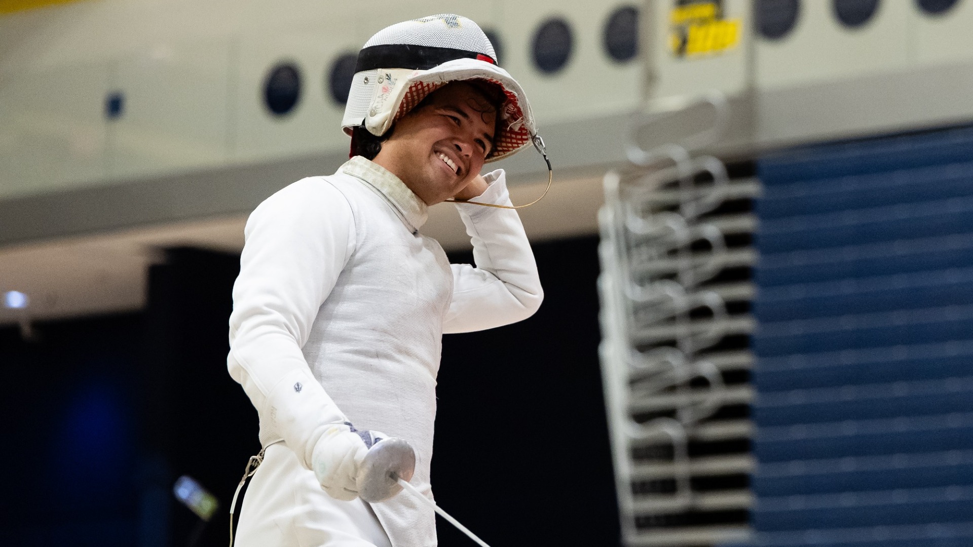 Jacob Levy smiling while taking off his fencing mask