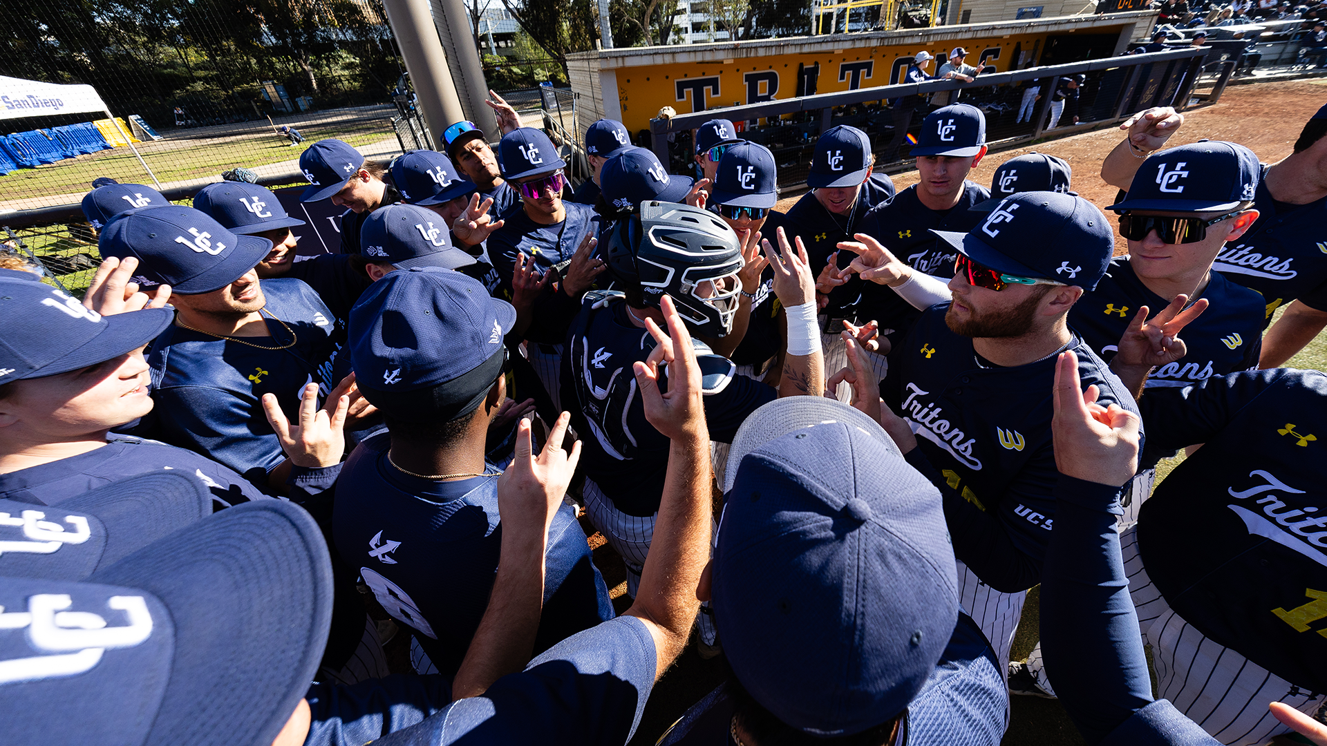 Baseball team huddles in front of dugout