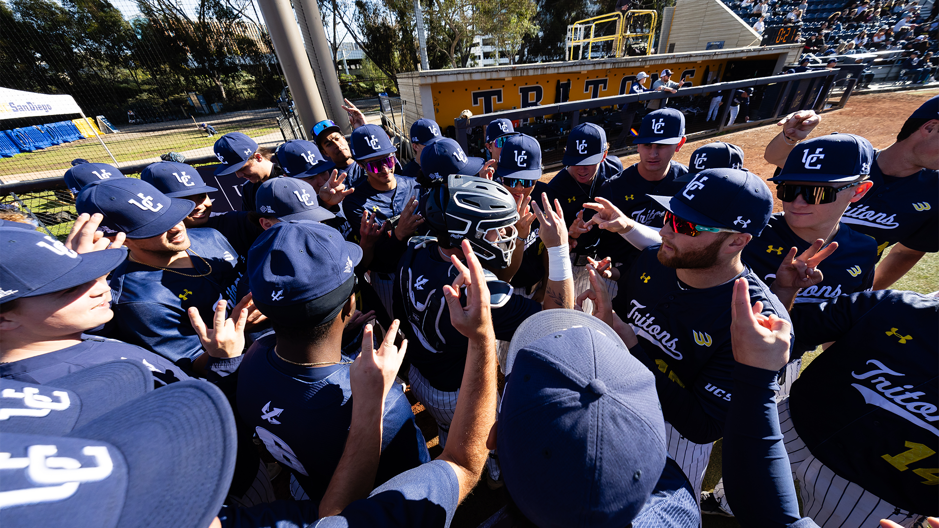 Team huddles in front of dugout vs BYU