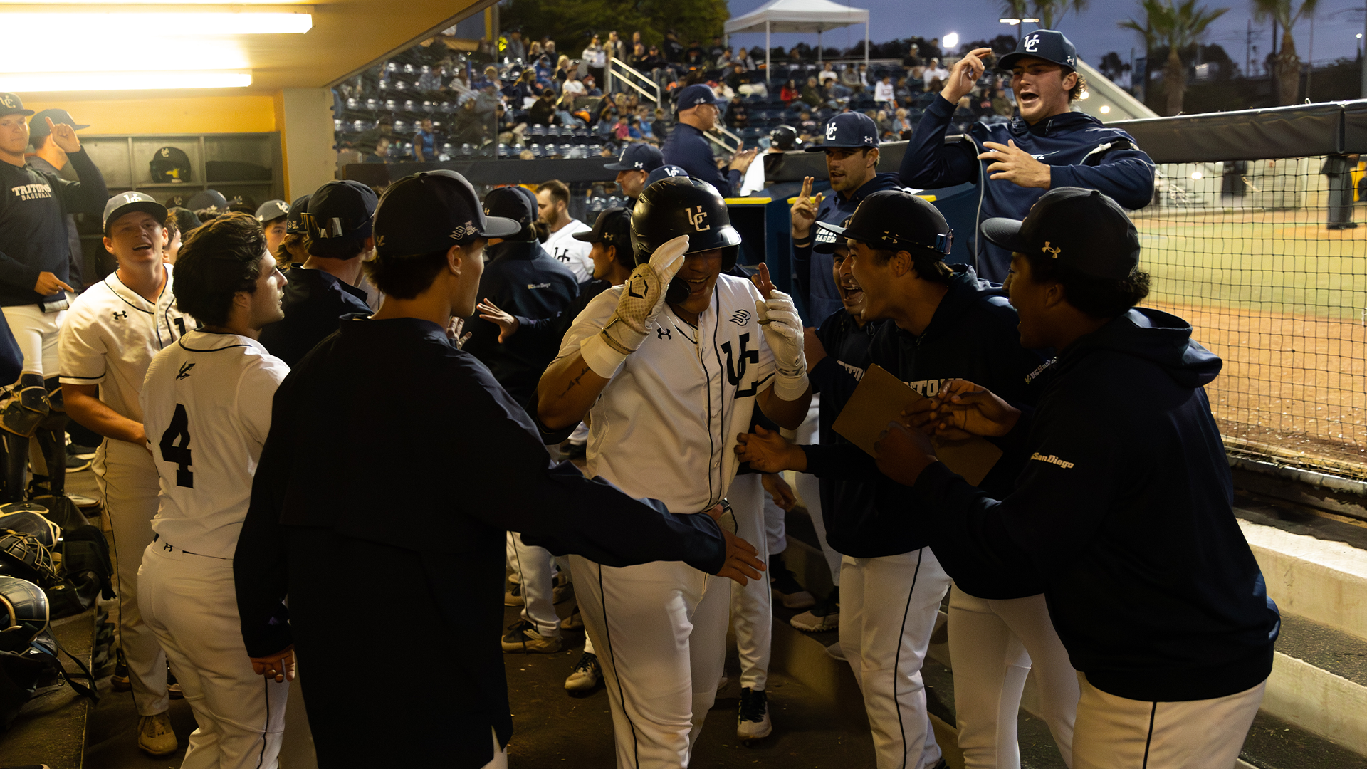 Gabe Camacho celebrates in dugout with teammates vs Fullerton