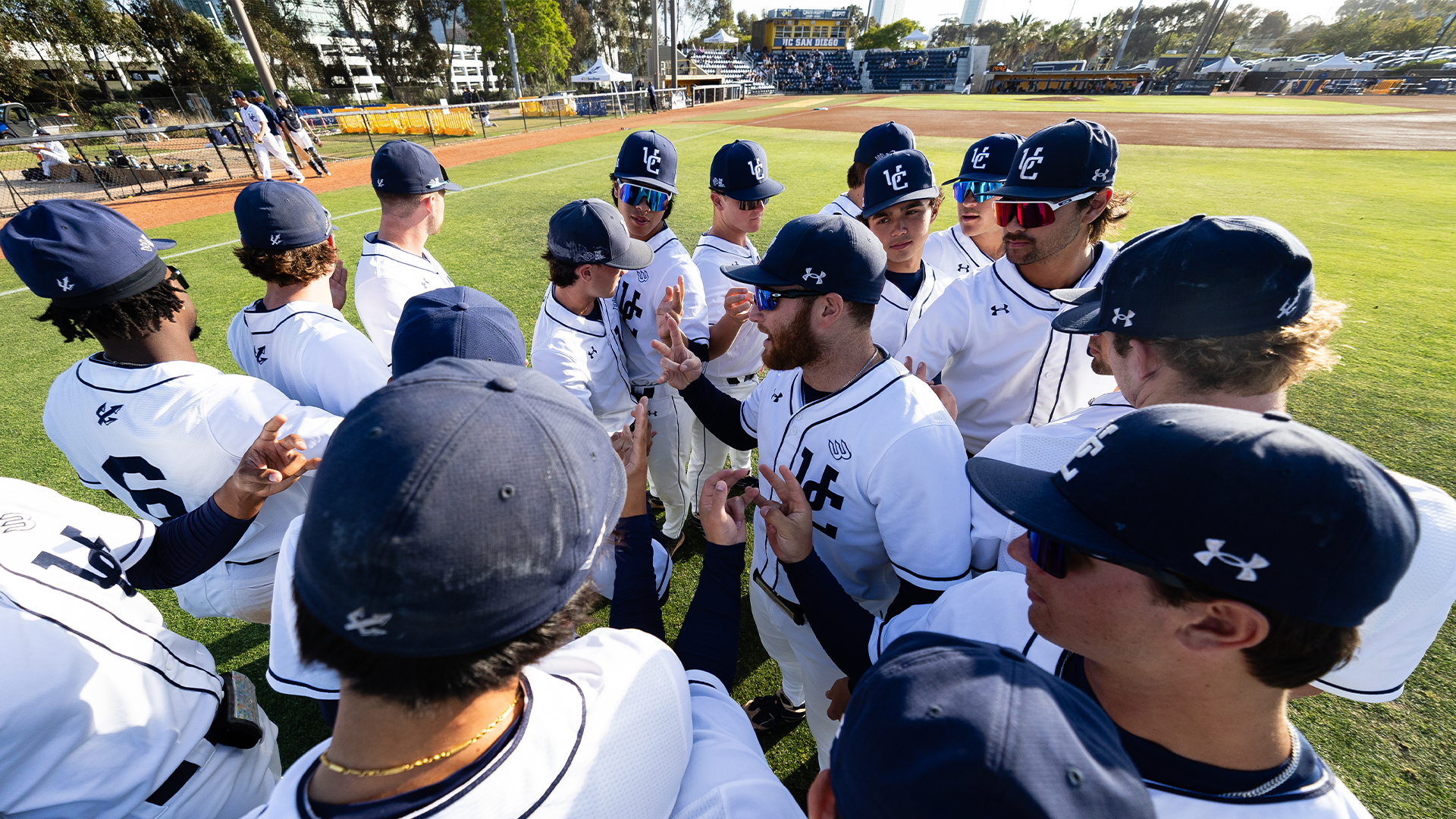 Baseball team huddles with stadium in the background