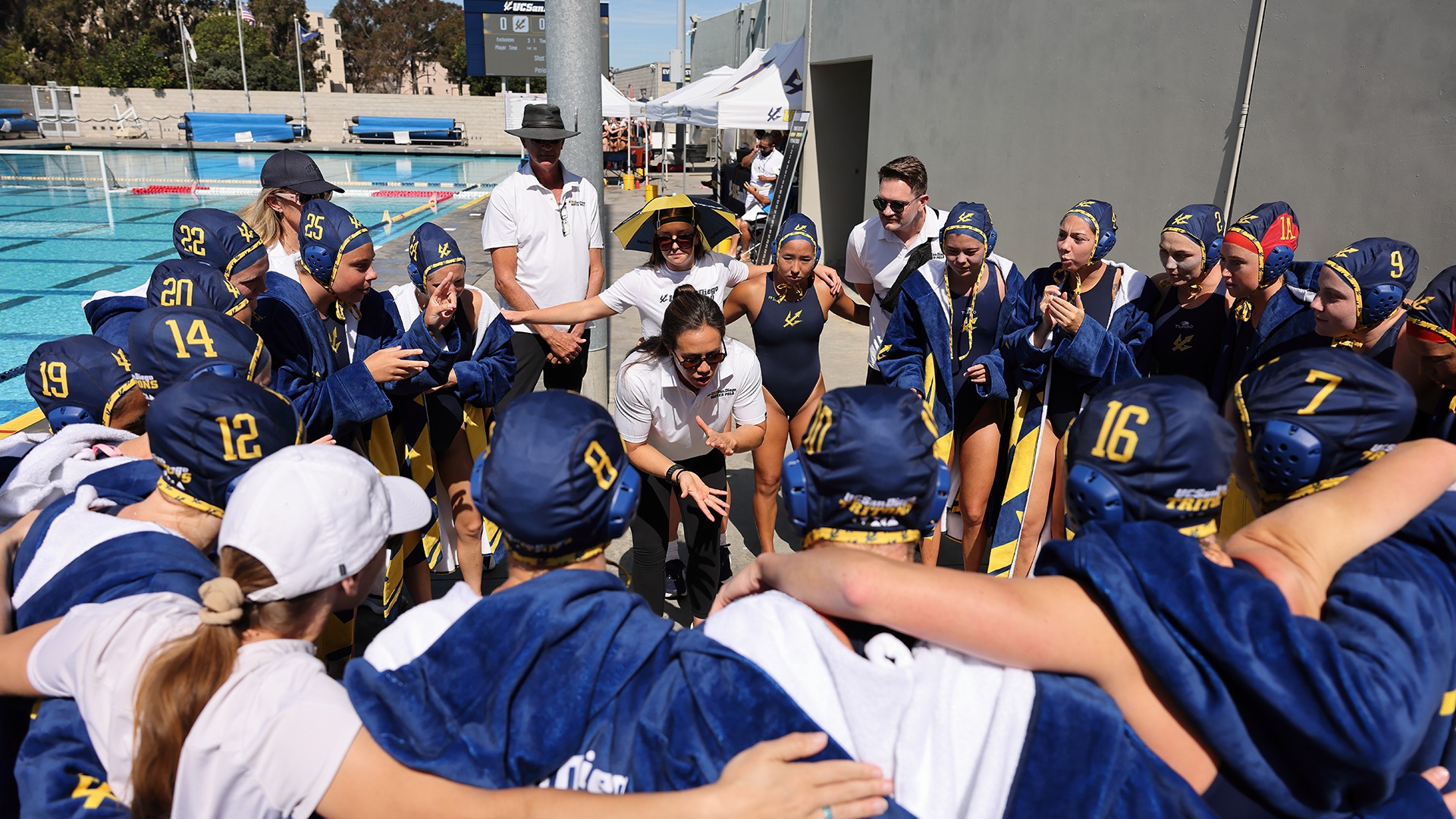 Women's water polo team huddle on the pool deck