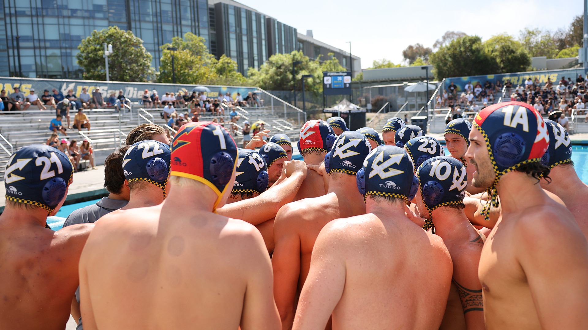 A group of Tritons gather on the pool deck during a timeout