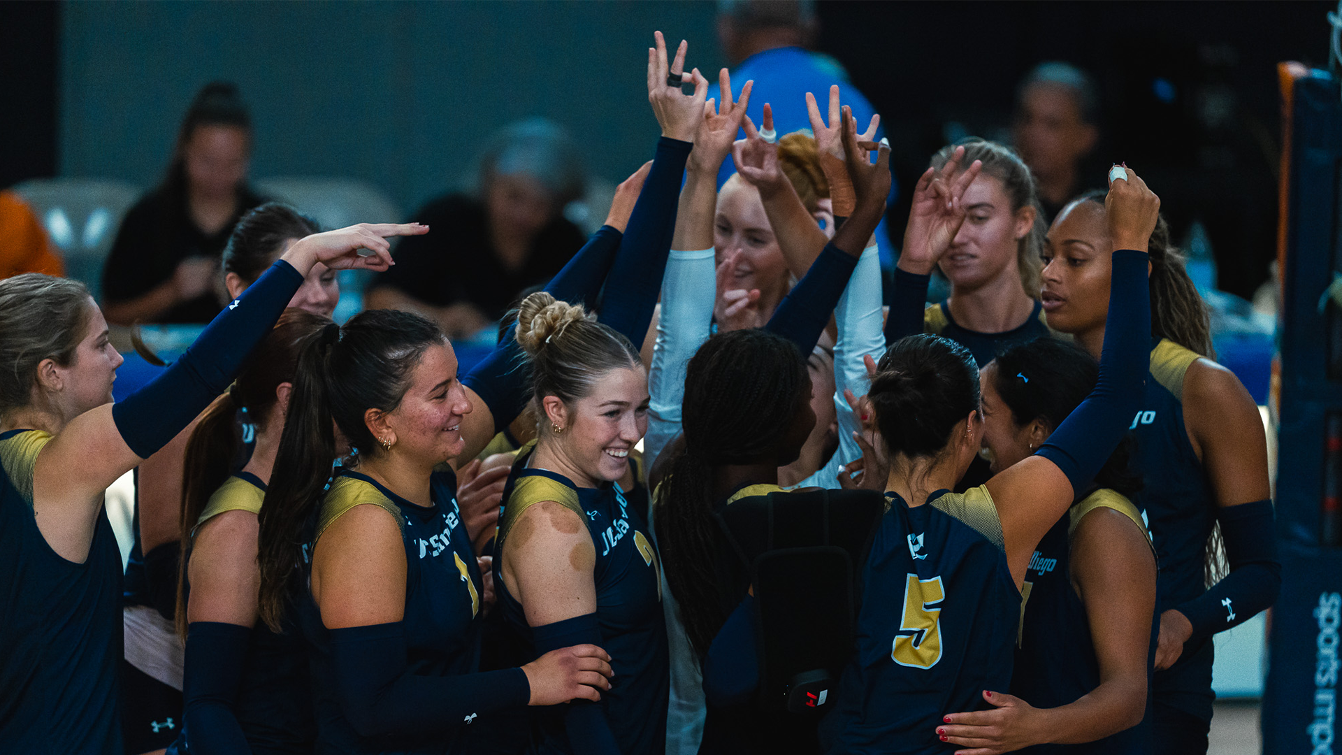 Volleyball huddles with trident fingers raised