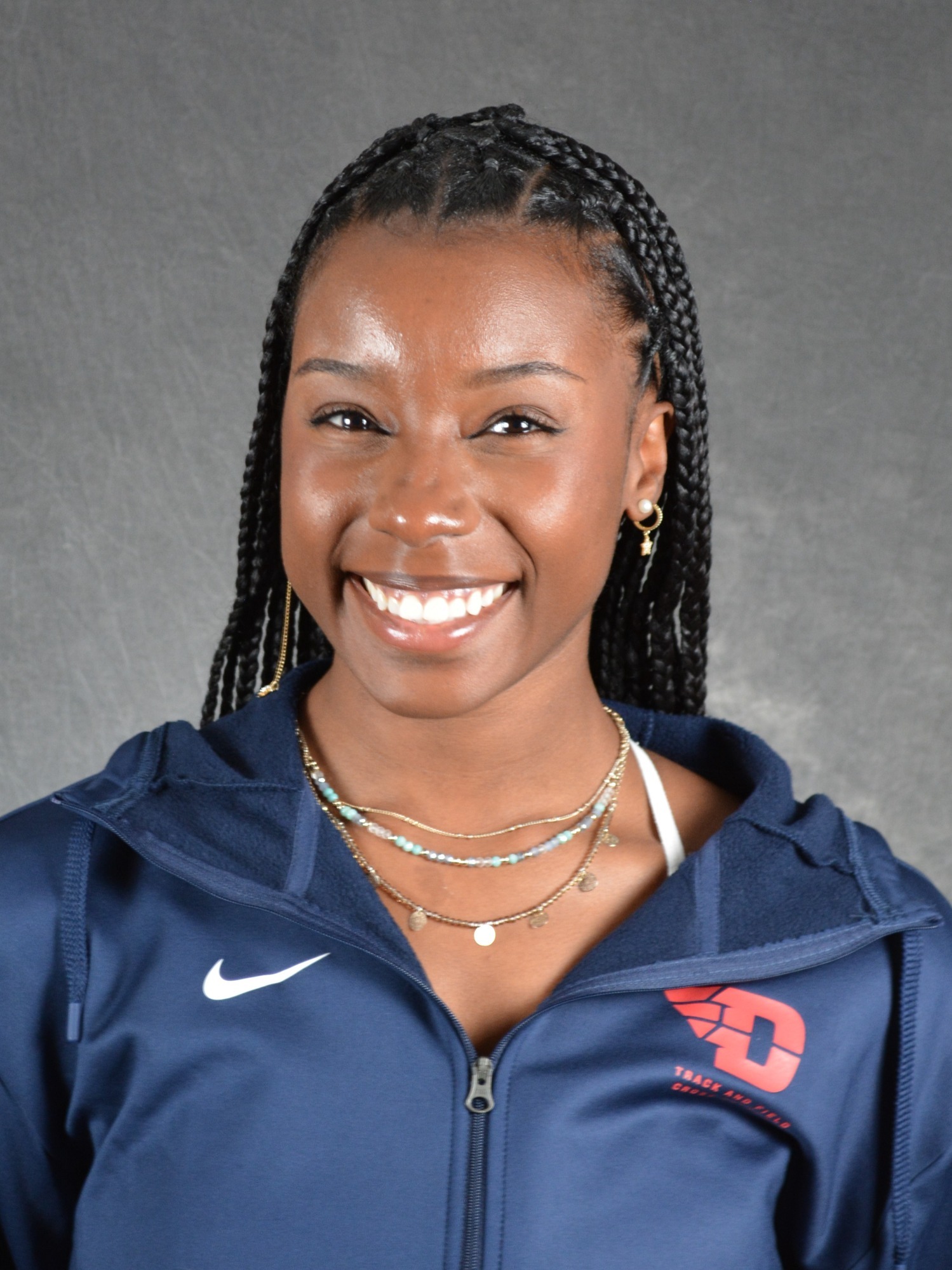 Jahmia Bridges-Butler poses for a headshot in a navy blue Dayton pullover with a red track and field/cross country logo.