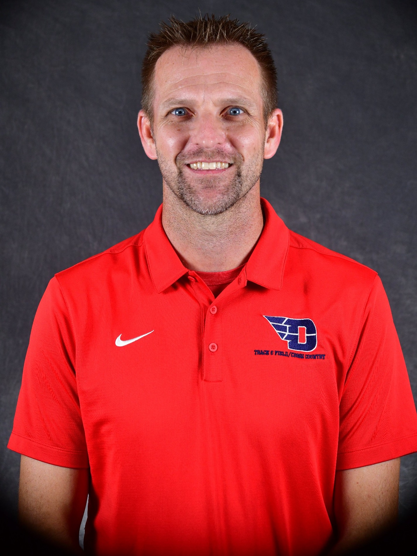 Coach David Dobson poses for his headshot in a red dayton polo.