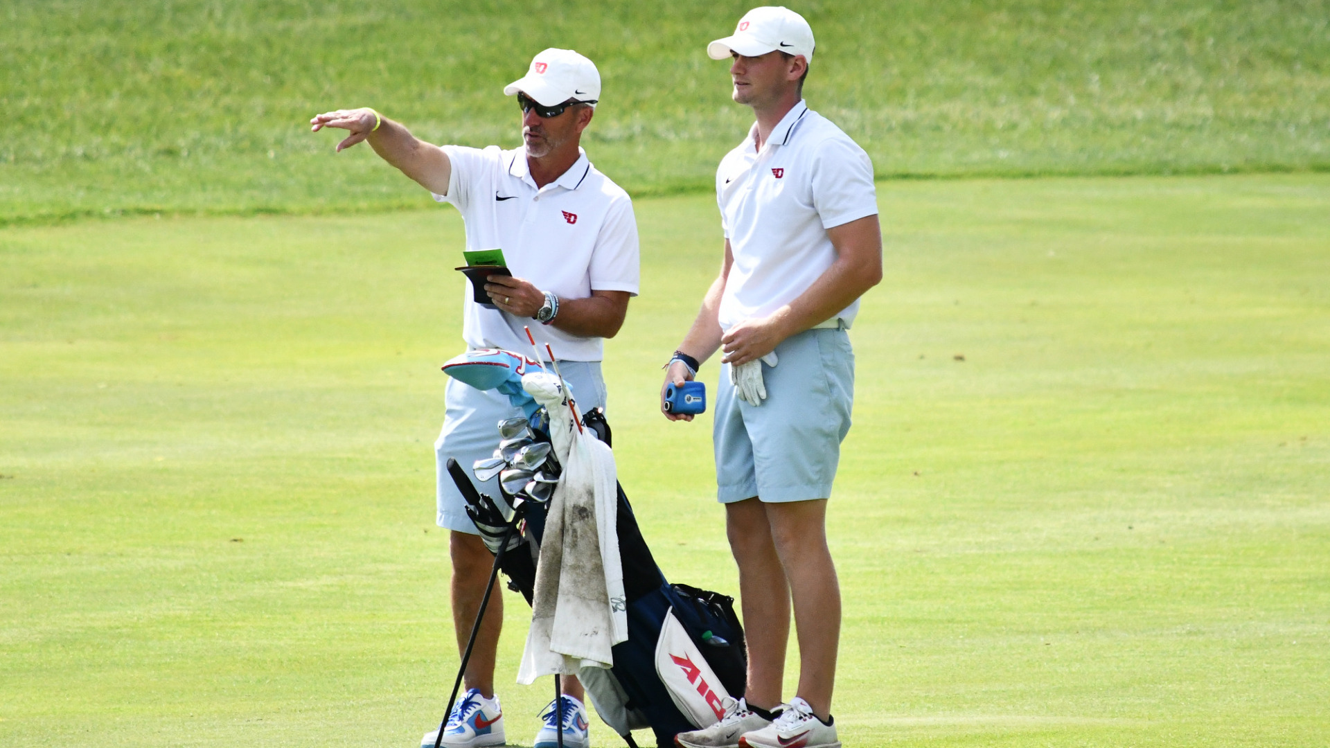 Men's golf head coach Gip Hoagland and player Ben Cors discussing strategy in the fairway during the 2025 NCAA Regional