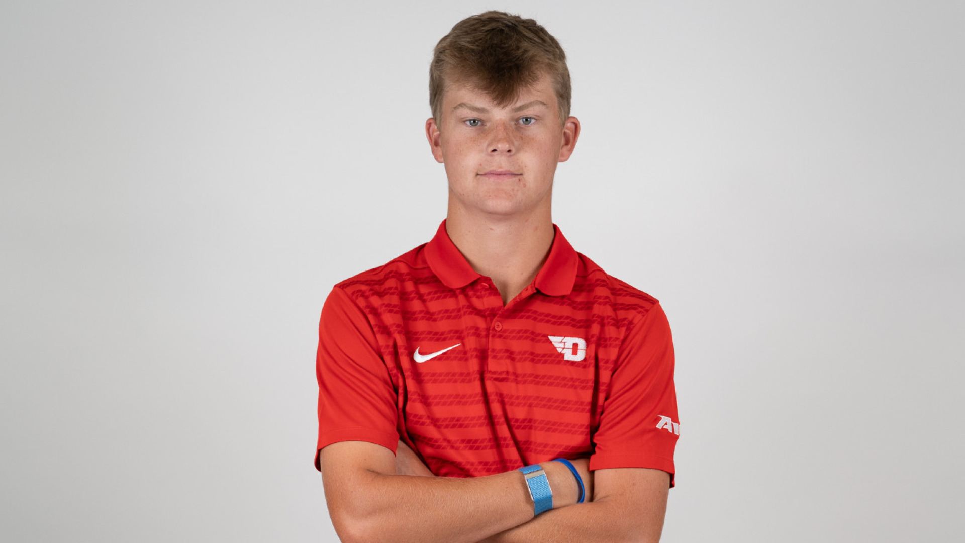 Men's golfer T.J. Kreusch, wearing a red polo-style shirt standing on a white background