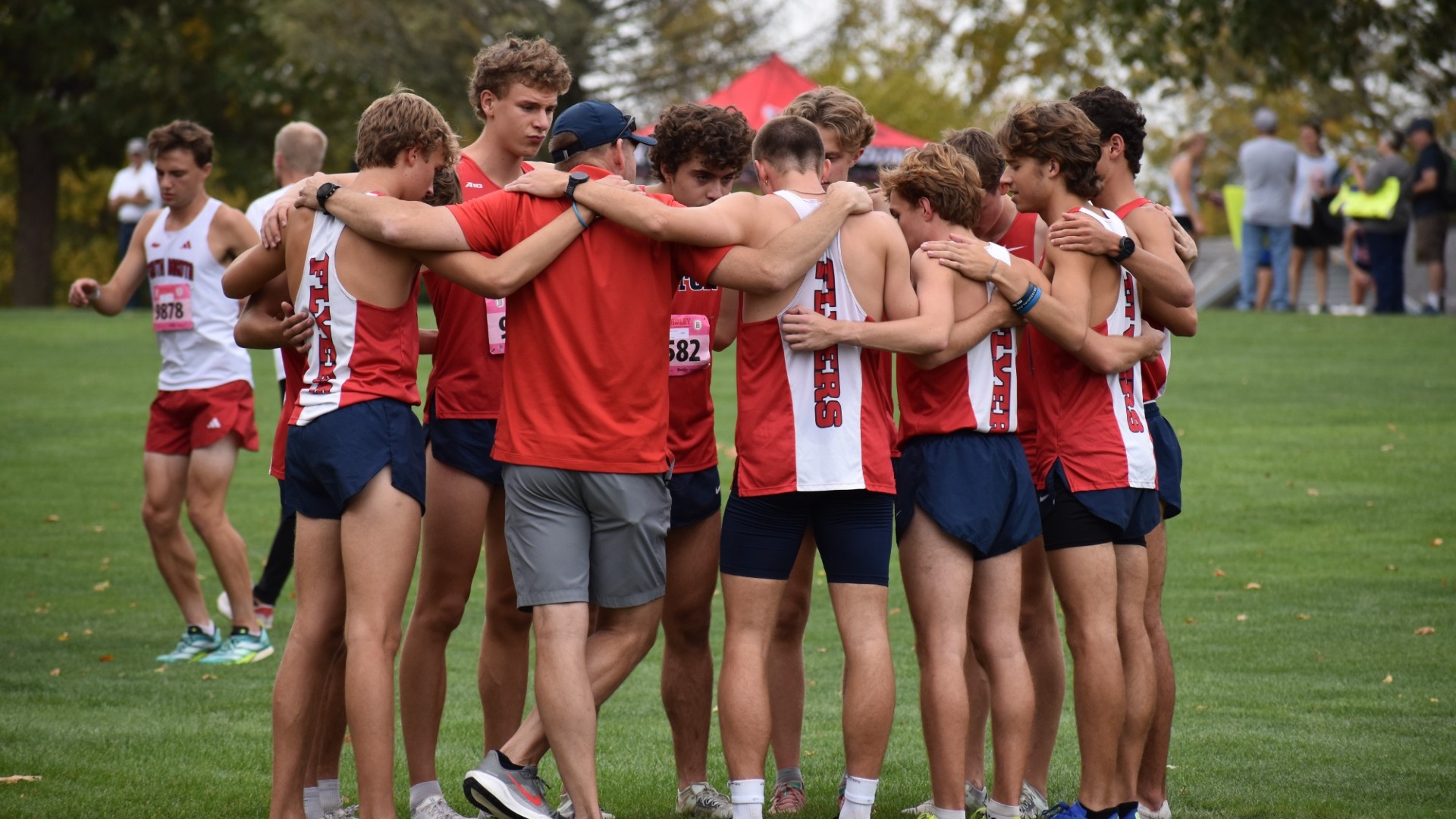UD Men's cross country team huddles with their arms around each other before a race