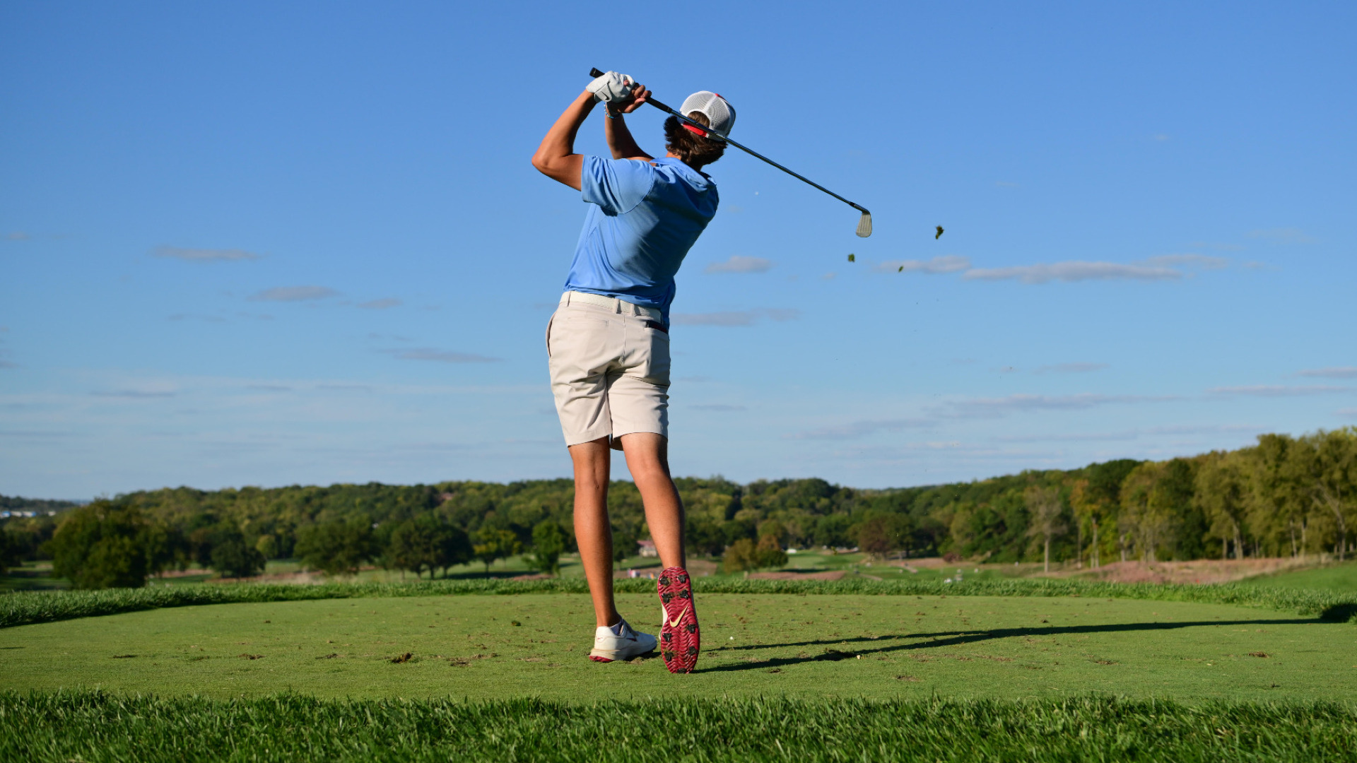 Men's golfer Victor Caliguri, wearing a light blue shirt and khacki colored shorts, shown from behind after teeing off at Moraine Country Club