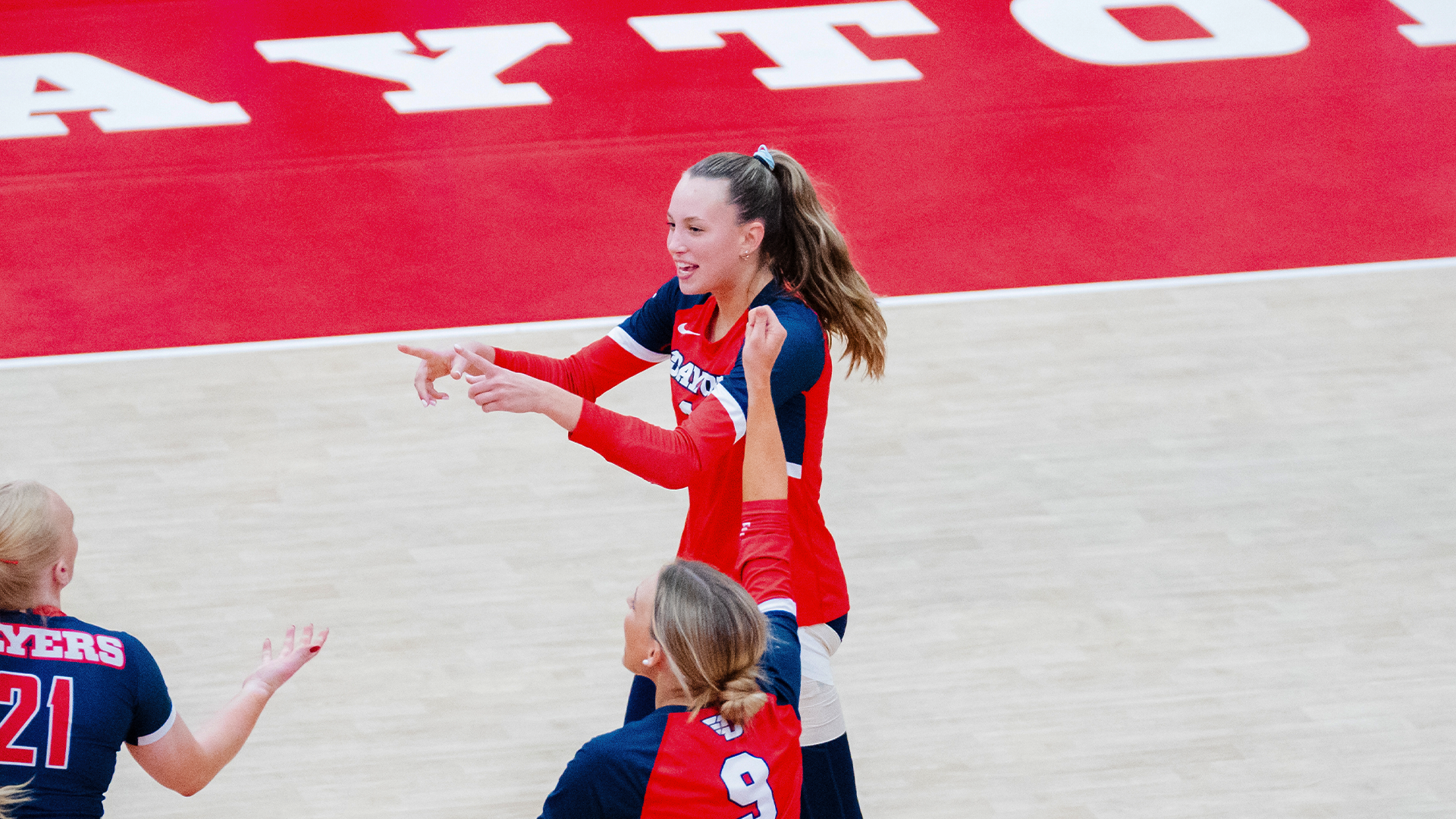 Kamryn Hunt points to her teammates in celebration after a point. She is in a red uniform.