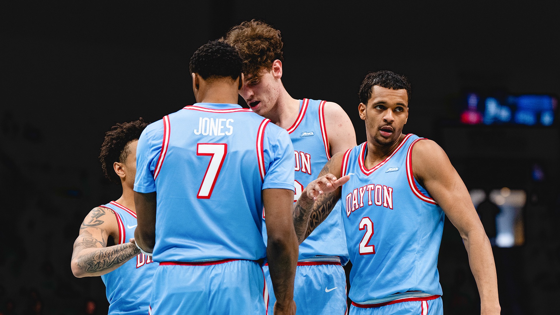 A group of Dayton Flyers, with Keonte Jones center, huddle against Virginia at the Spectrum Center