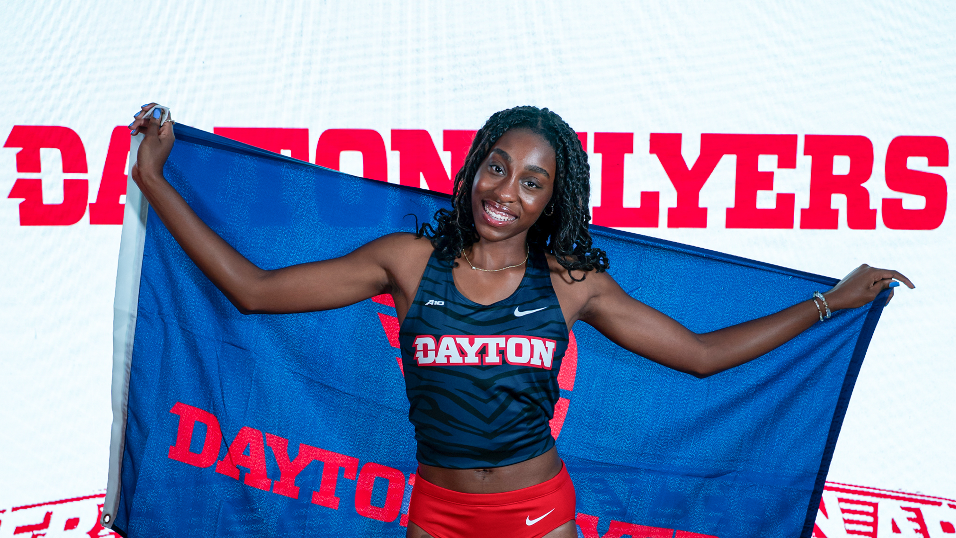 Simone Bessong holds up a Dayton Flyers flag and smiles on content day.
