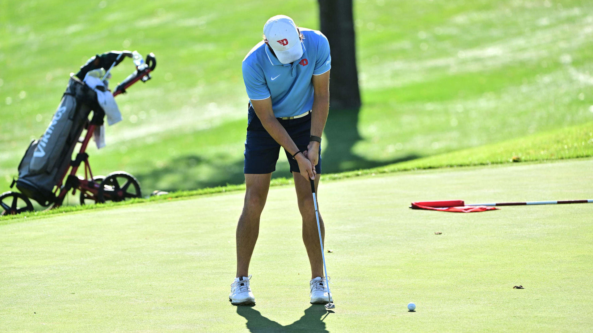 Men's golfer Breckin Taylor putting the ball toward the hole on a green at NCR Country Club
