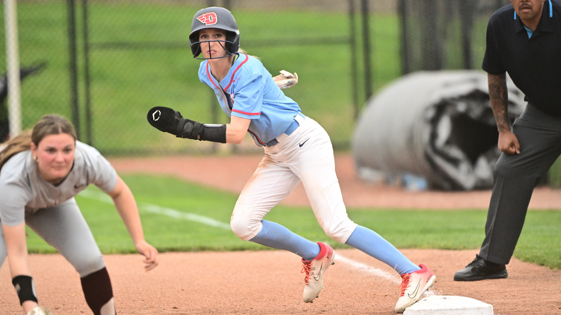 Emma Schutter wearing a Chapel blue jersey top and white uniform pants about to take off running from first base during a games against Fordham at UD Softball Stadium