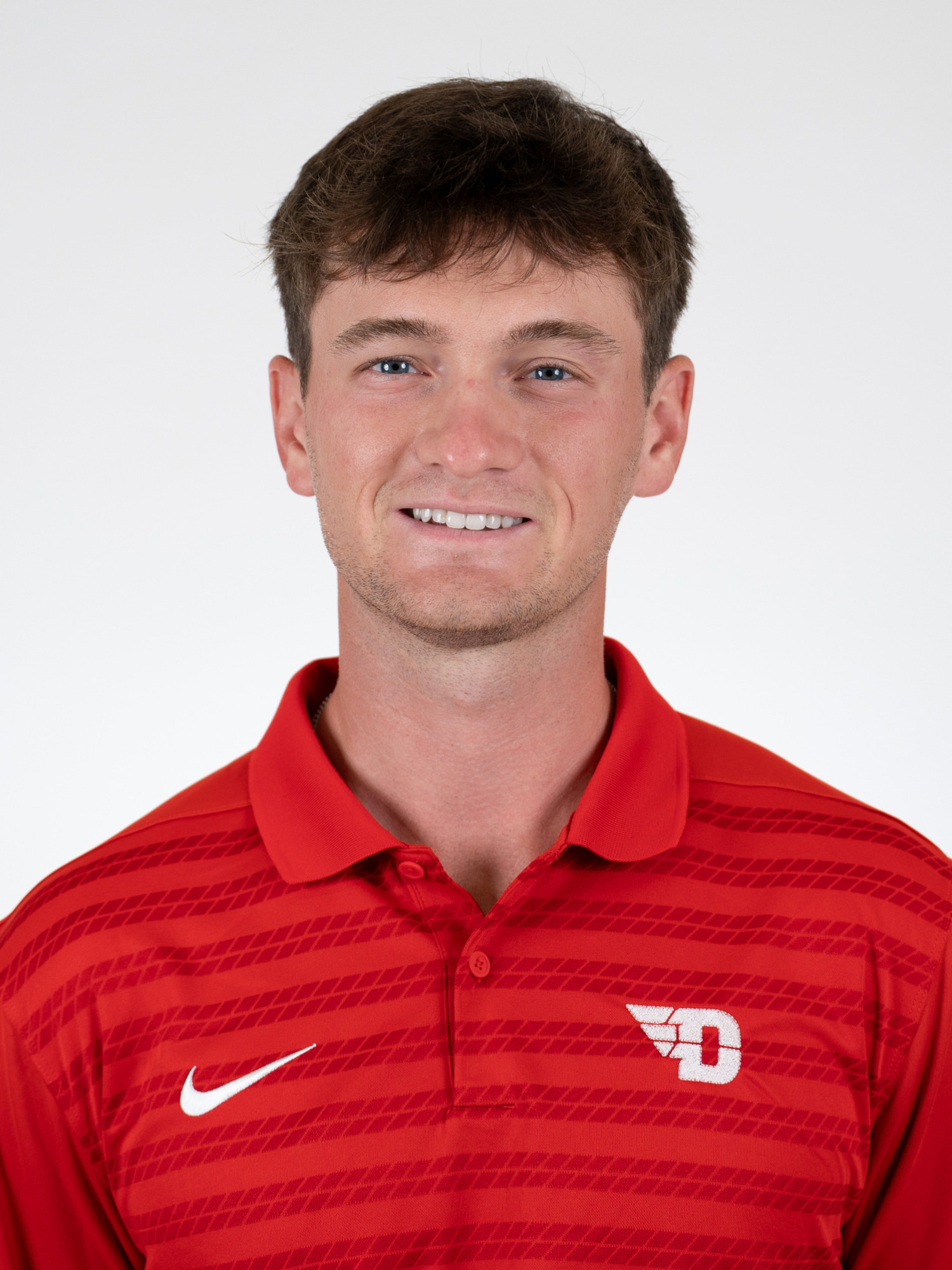 Potrait image of Ben Cors wearing a red polo-style shirt with a white winged-D Dayton logo