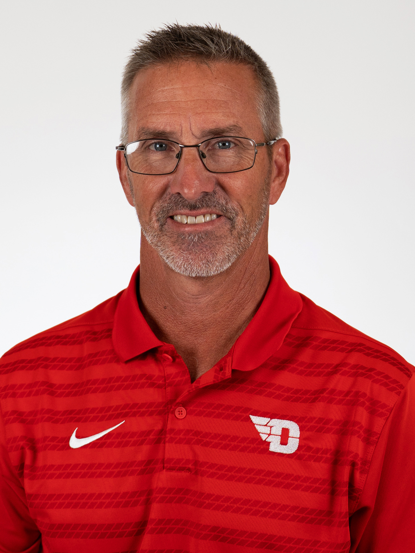 Potrait image of Gip Hoagland wearing a red polo-style shirt with a white winged-D Dayton logo