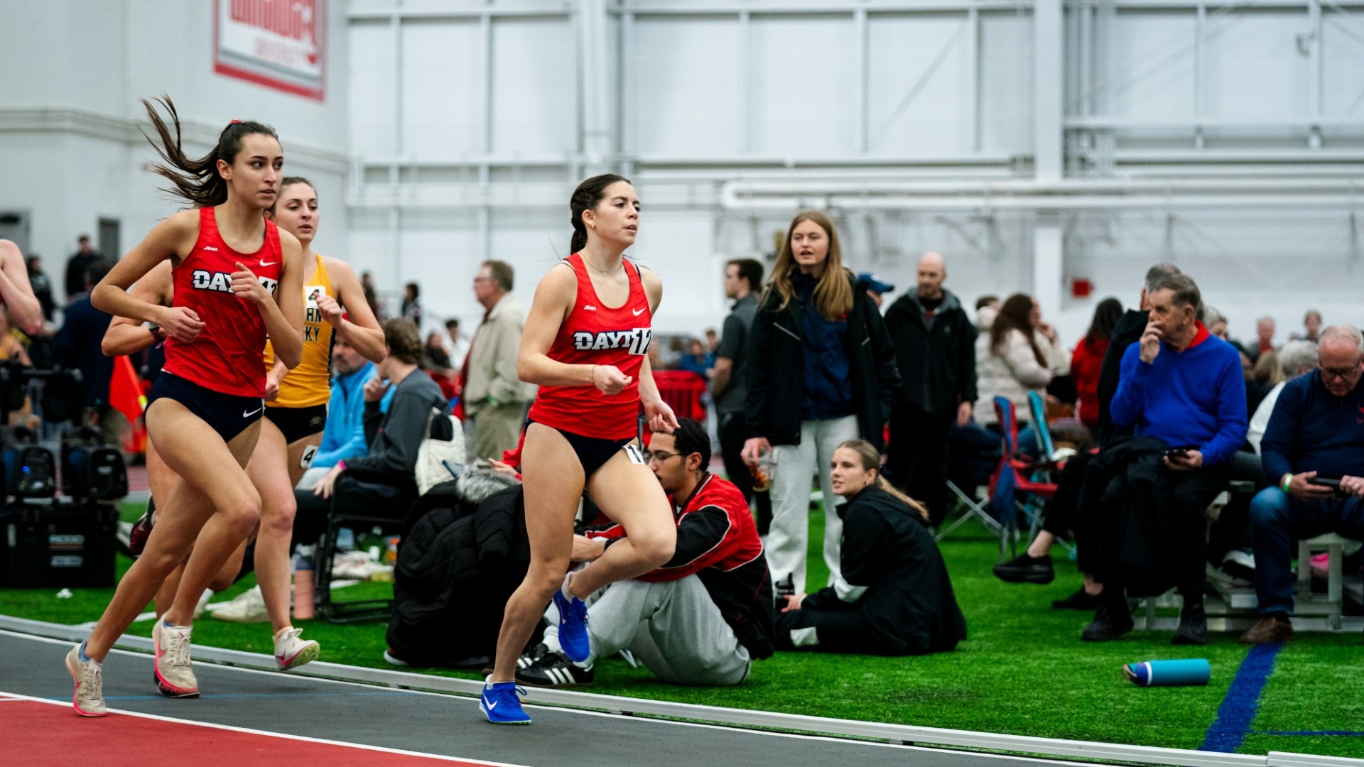 Mia Gill and Olivia Kindbom run close to each other as they round a curve at Gem City Invitational