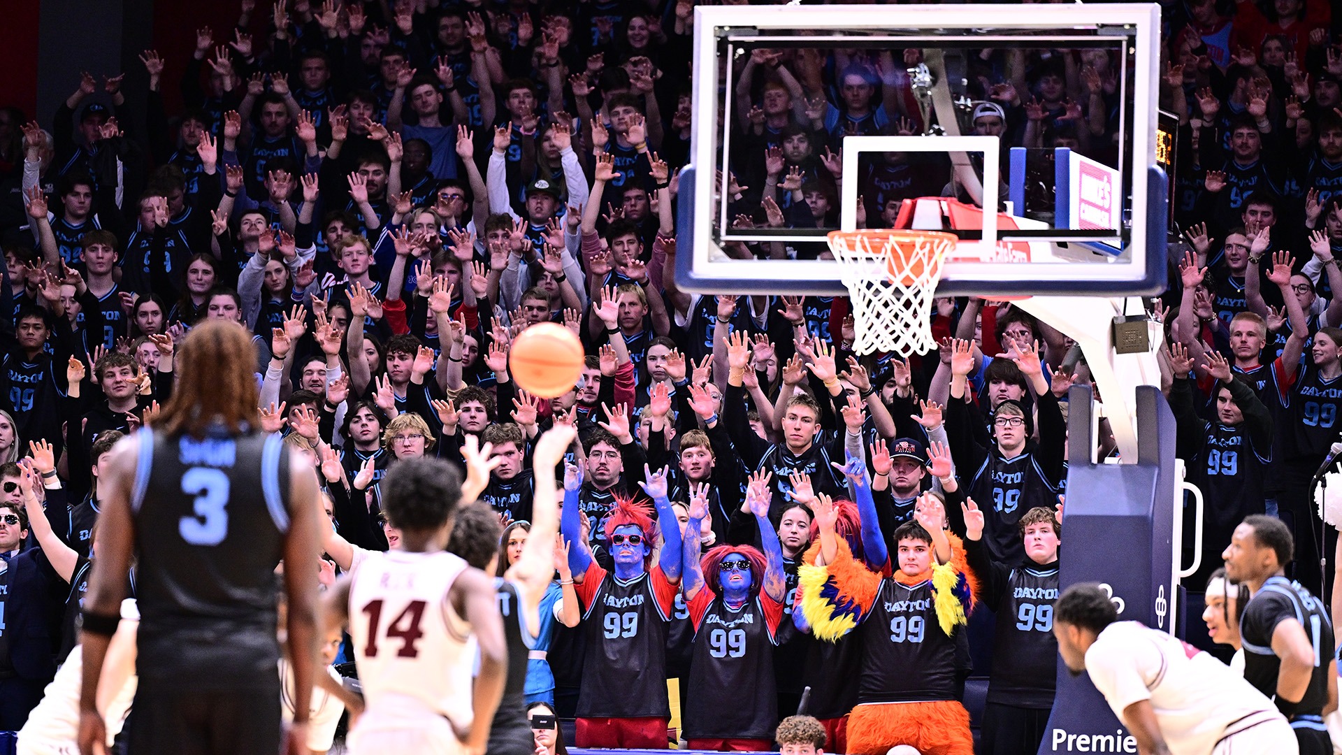 The University of Dayton student section, the Red Scare, holds its hands up while a Flyer shoots a free throw.
