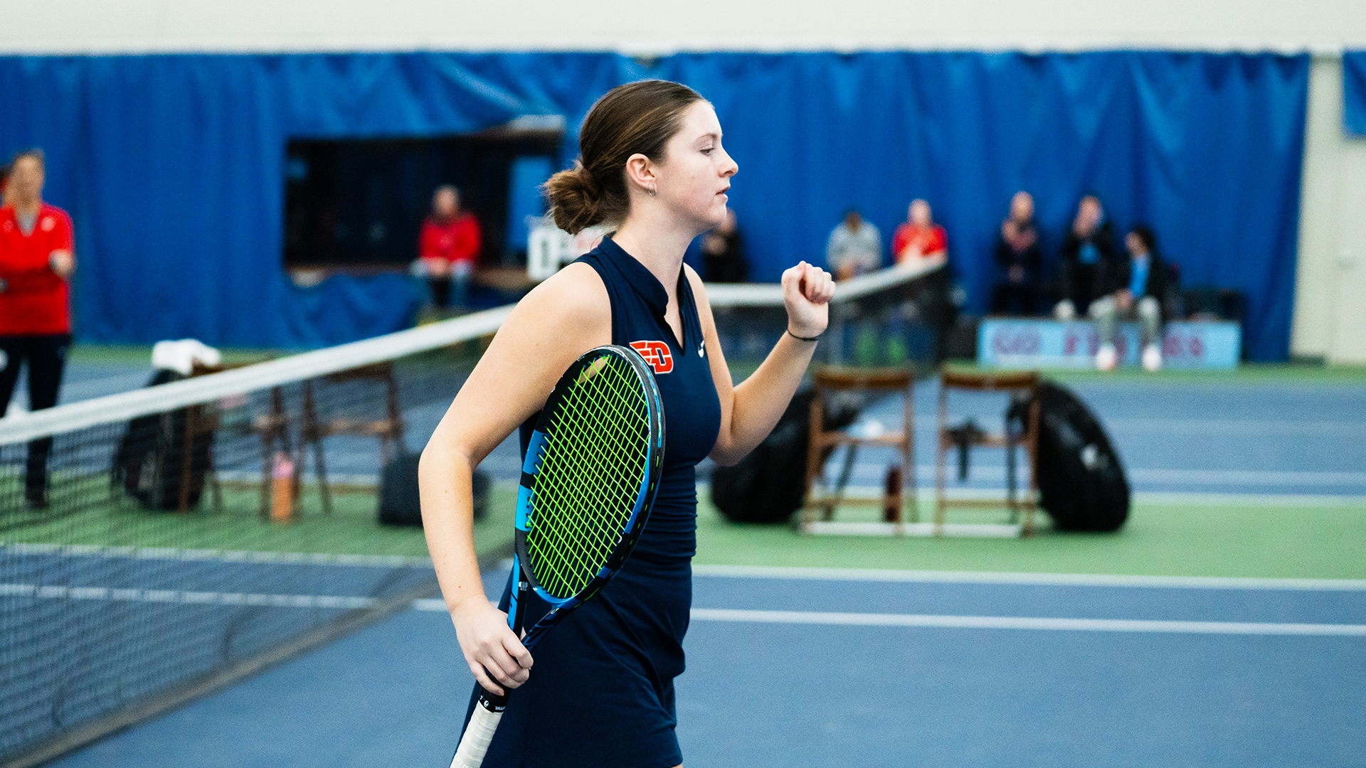 Baby Jordan runs on the court, swinging her left arm and holding her racquet in her right hand.