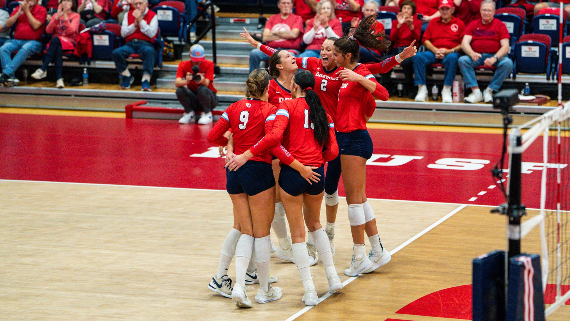Dayton Flyers team huddling in on the court to celebrate.