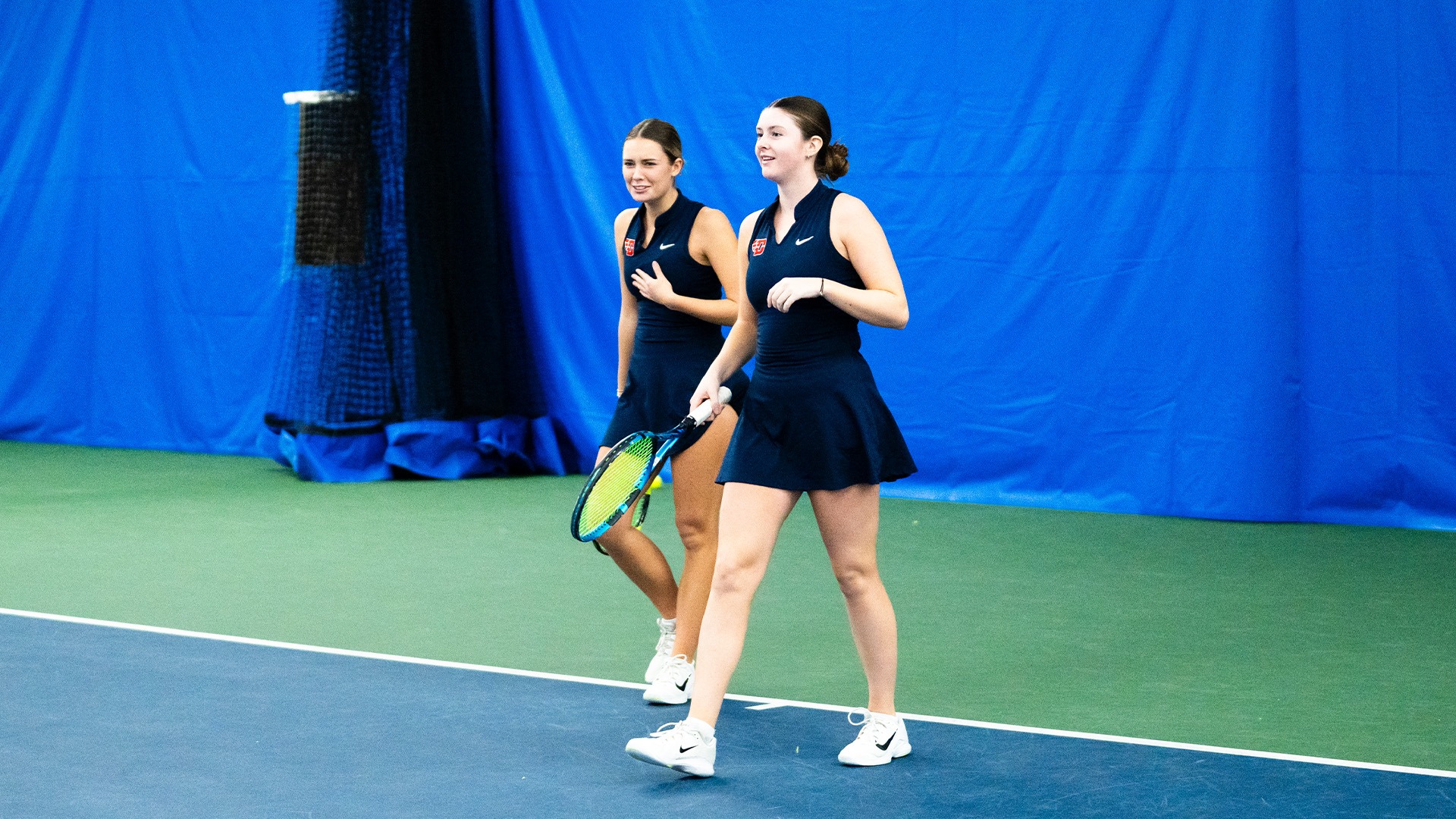 Mallory Hitchcock and Baby Jordan walk towards the net. They are both wearing navy uniforms.