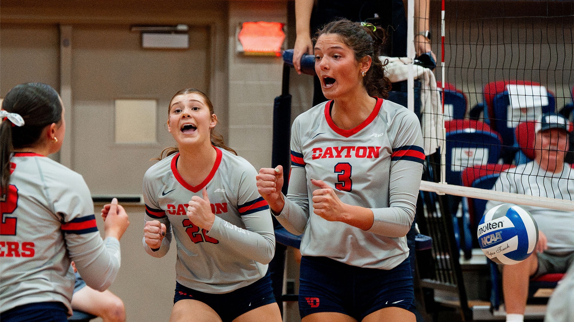 Abigail Cresse celebrates with teammates after a point. They are wearing grey jerseys.