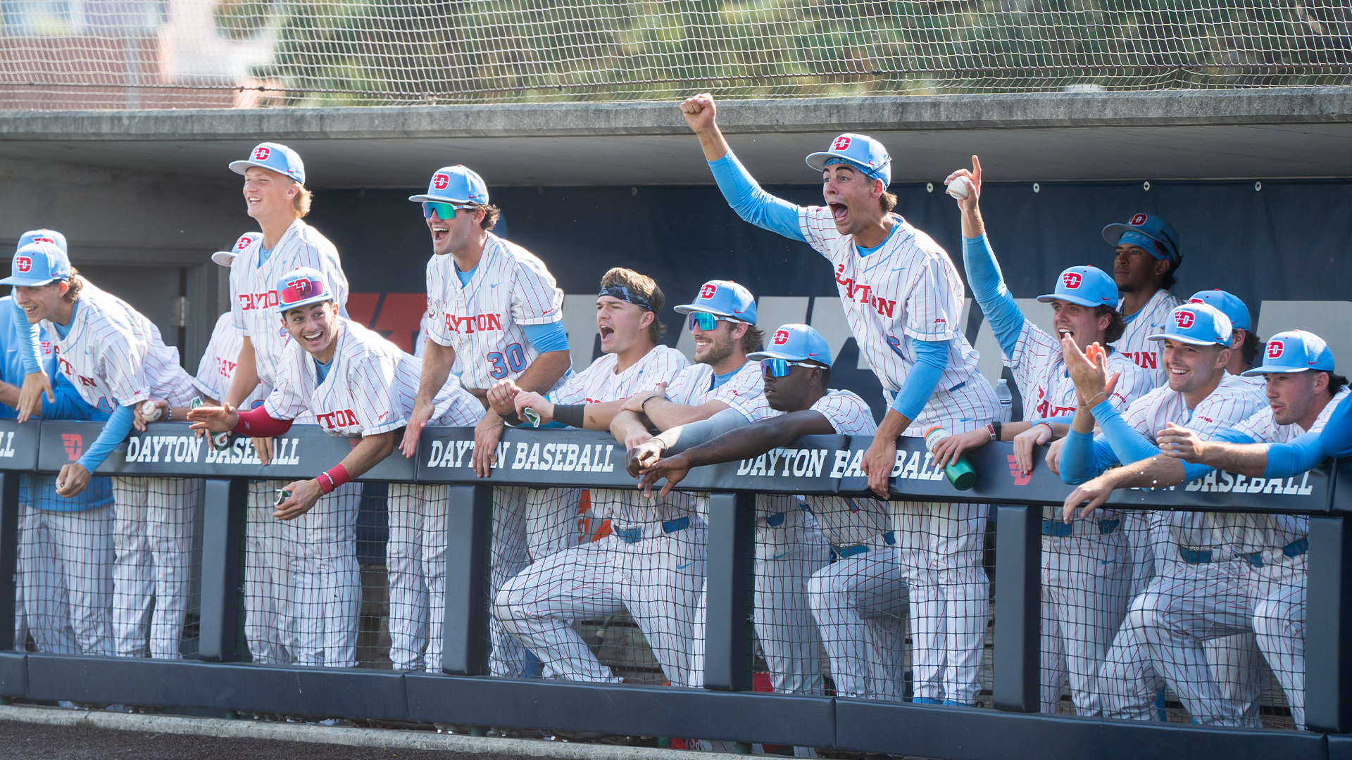 Players yell and celebrate in the dugout at Woerner Field at AES Ohio Stadium.