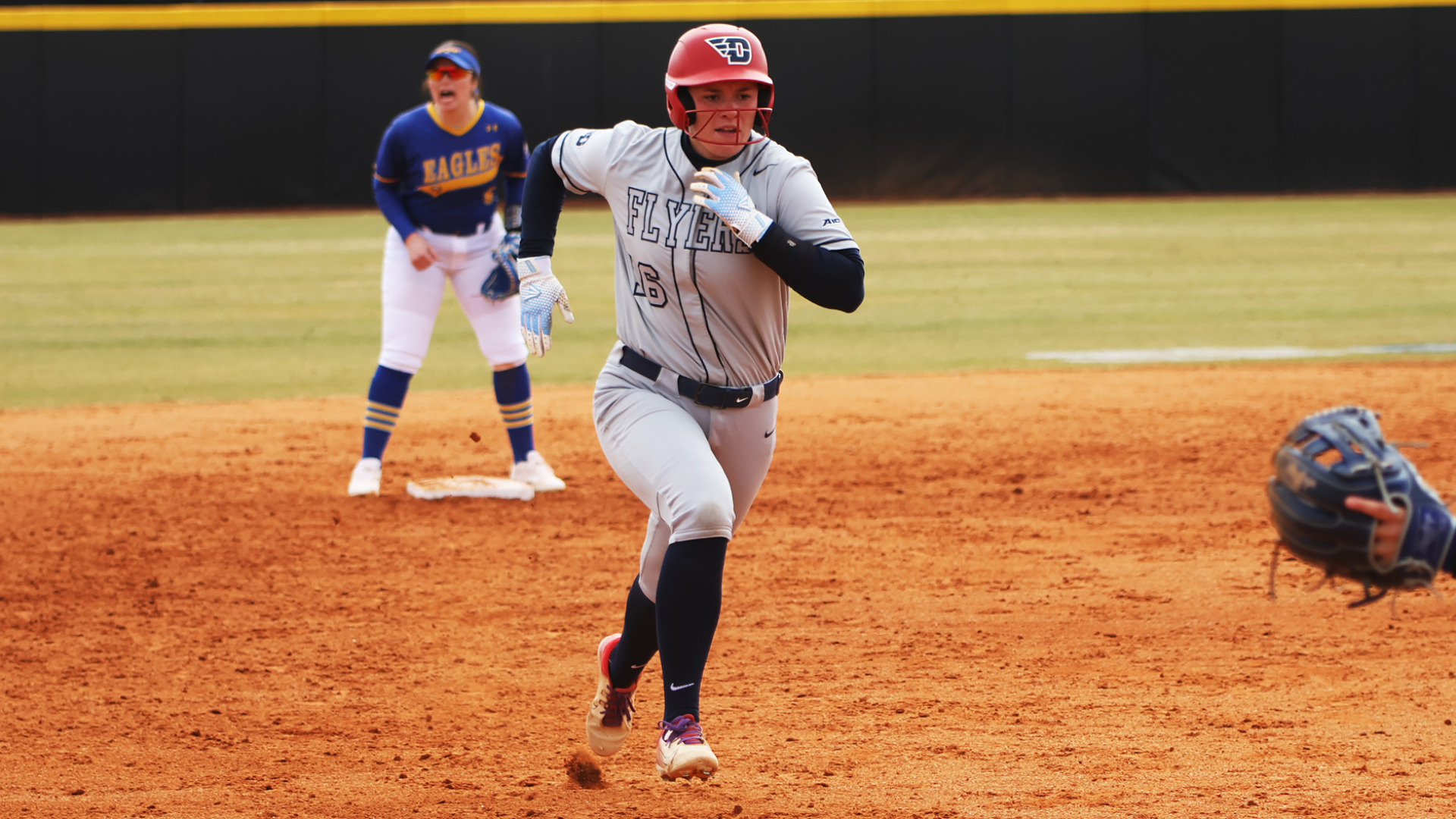 Softball's Katelin Goodwin, wearing a gray uniform top and bottom, running between second and third base in a game against Morehead State