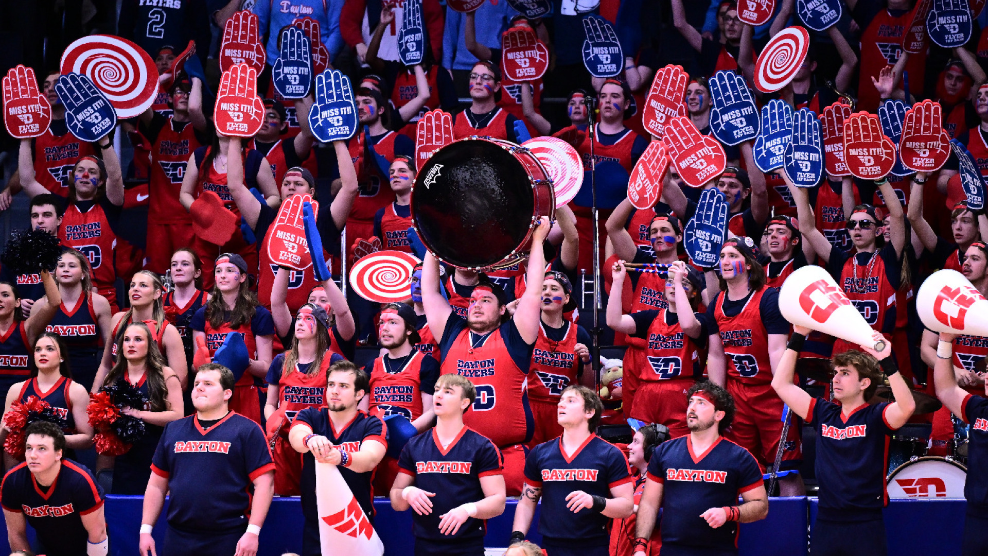 Members of the Flyer Pep Band stand and cheer and hold up foam fingers during an opponent's free throw attempt at UD Arena