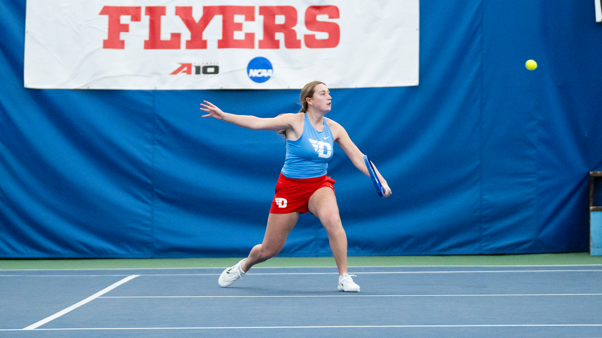 Caroline Boyle backhands the ball. Her racquet is in her left hand.